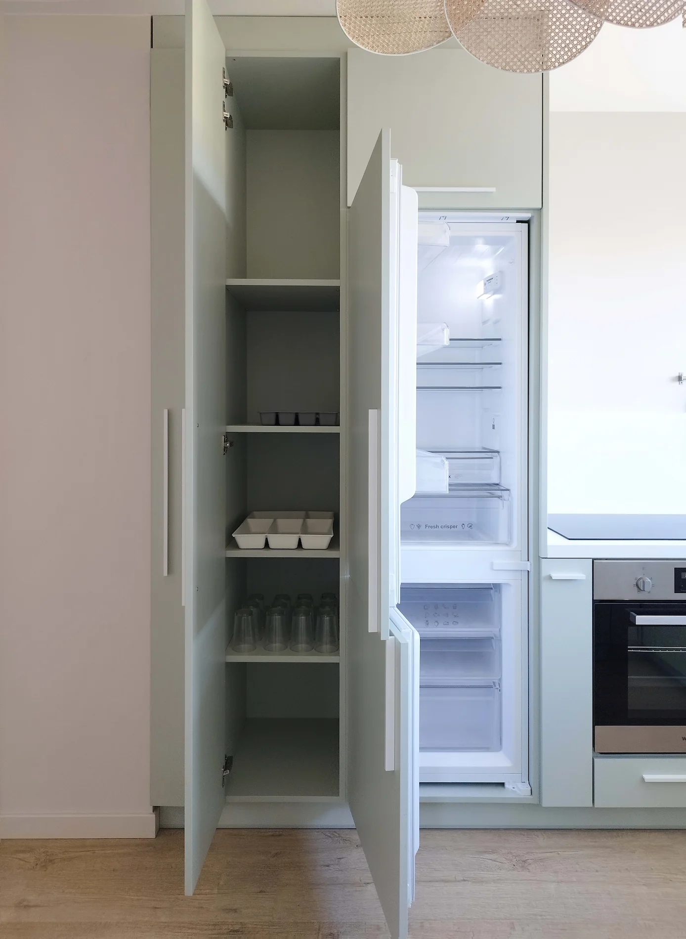 Colonne de rangement et réfrigérateur intégré ouverts dans la cuisine repensée de l’appartement.