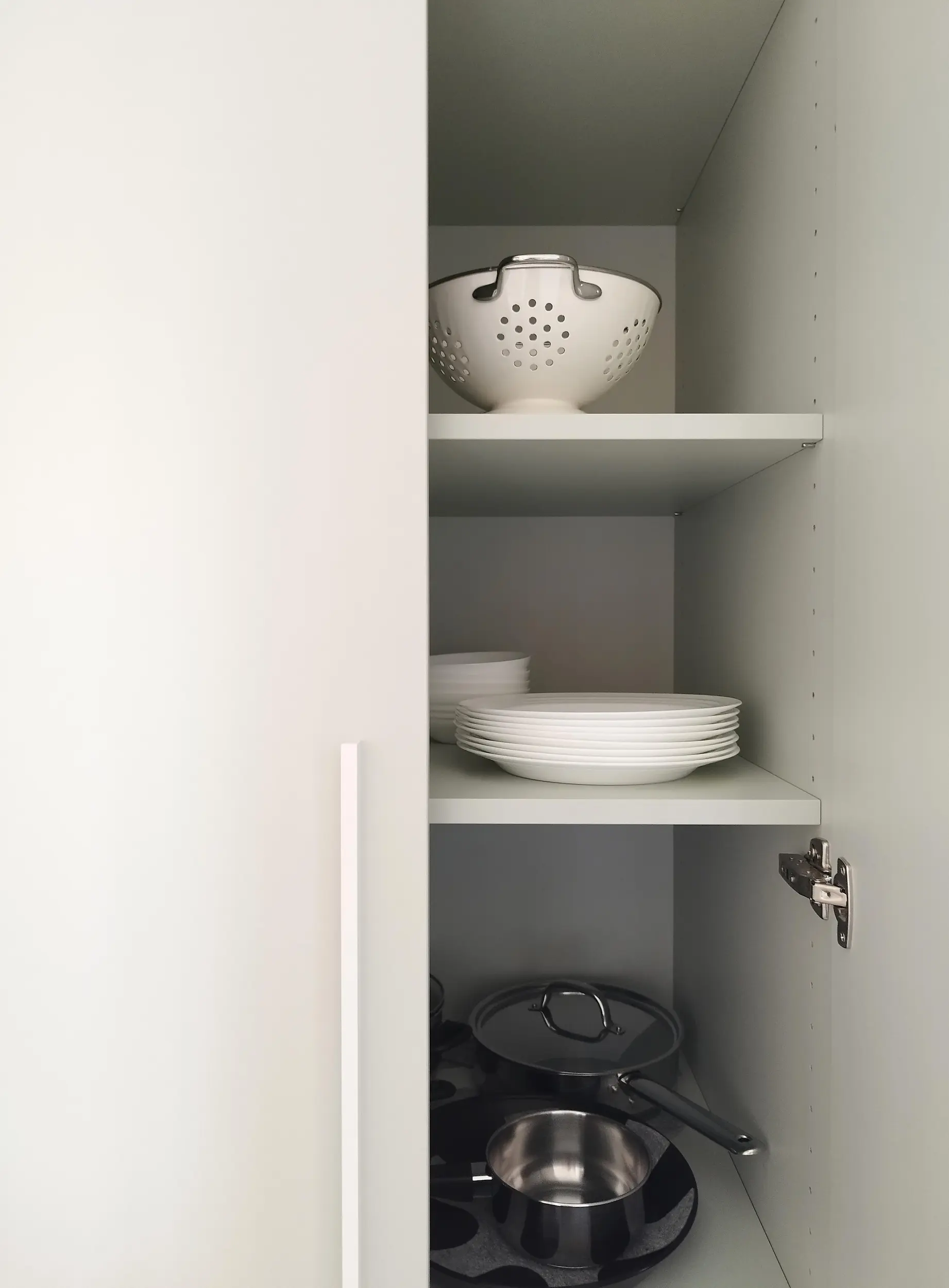 Intérieur d’un meuble de cuisine rénové montrant l’organisation des étagères et de la vaisselle.