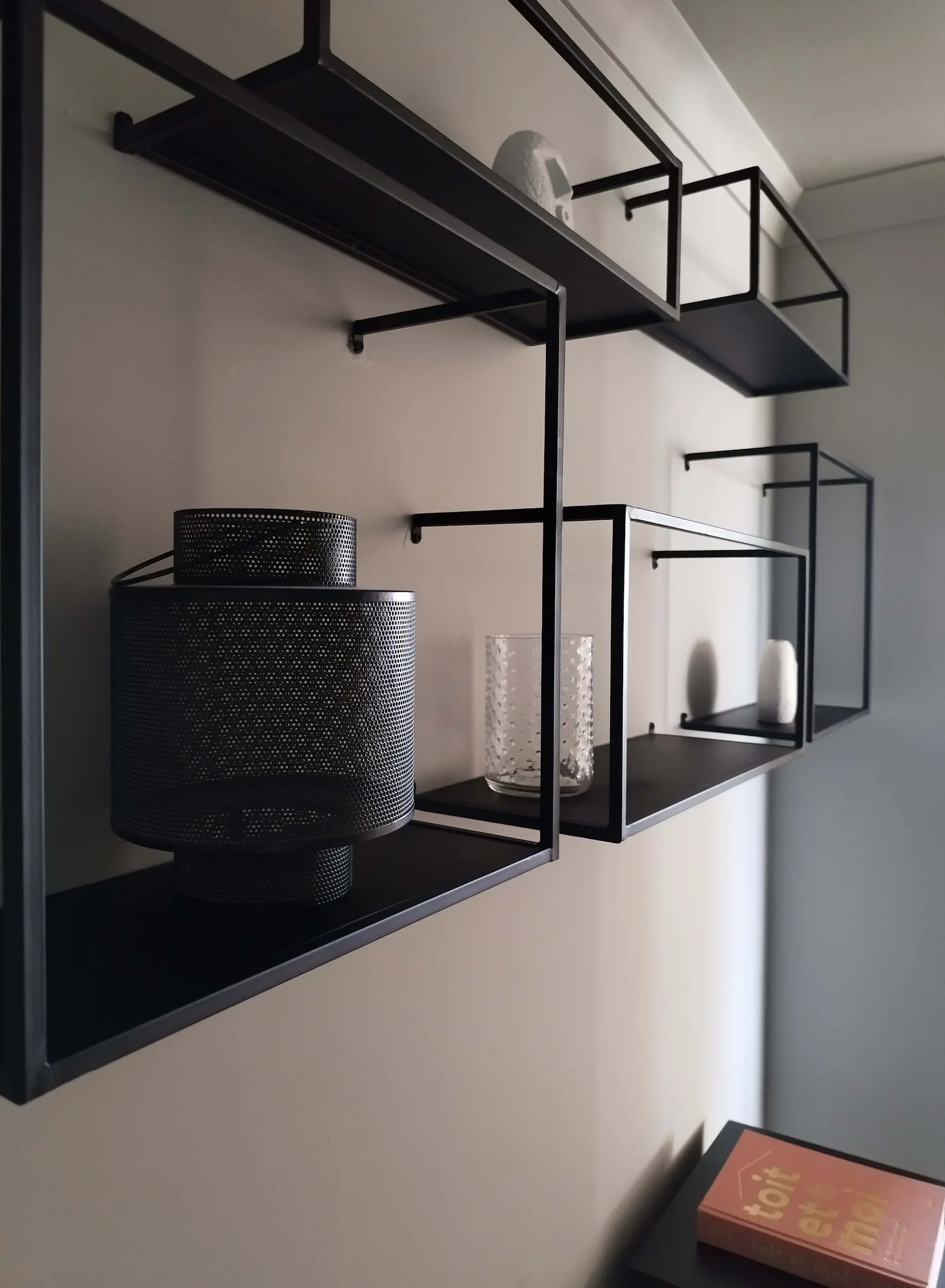 Étagères murales en métal noir installées dans l’entrée repensée pour un style contemporain et graphique.