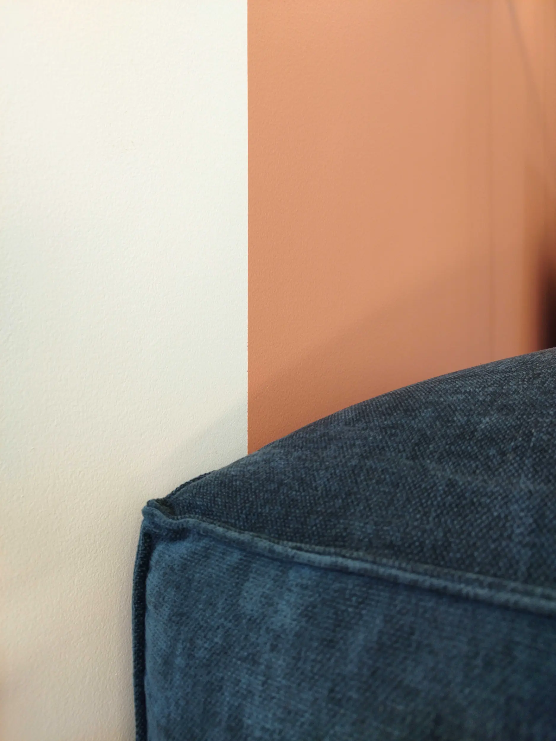 Gros plan sur l’association d’un mur terracotta et d’un coussin bleu texturé dans le salon rénové.