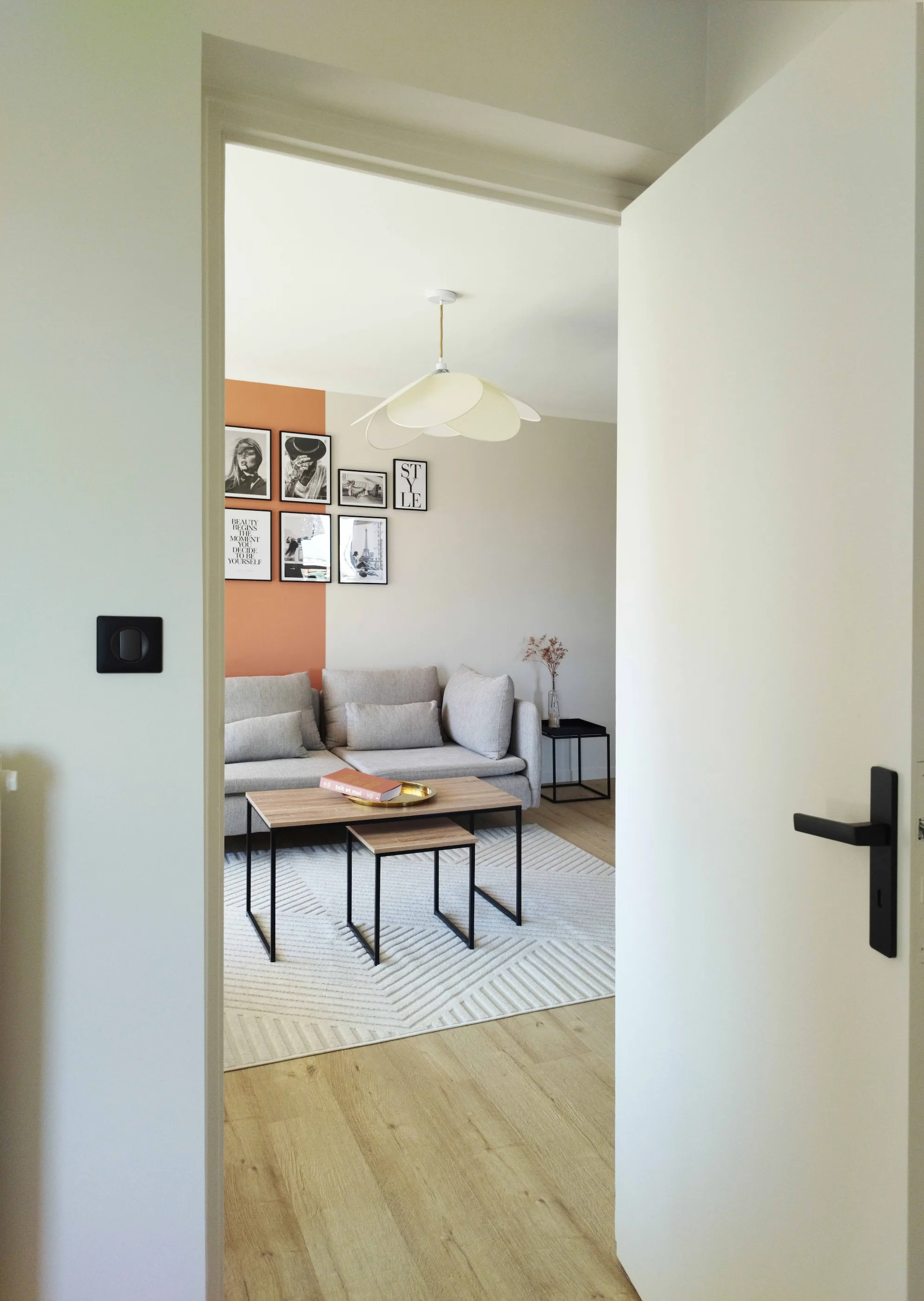 Perspective depuis l’entrée révélant le salon lumineux, ses tons naturels et la mise en scène murale de cadres.