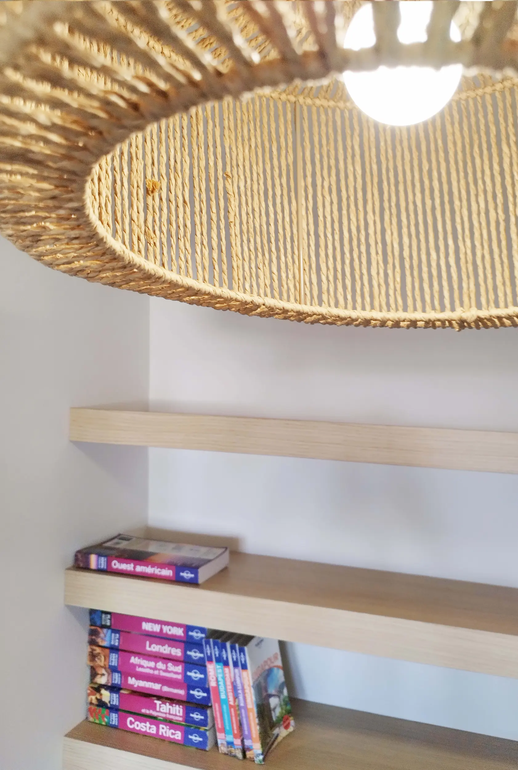 Suspension en rotin éclairant des étagères murales en bois, détail déco conçu par jiwa.a.