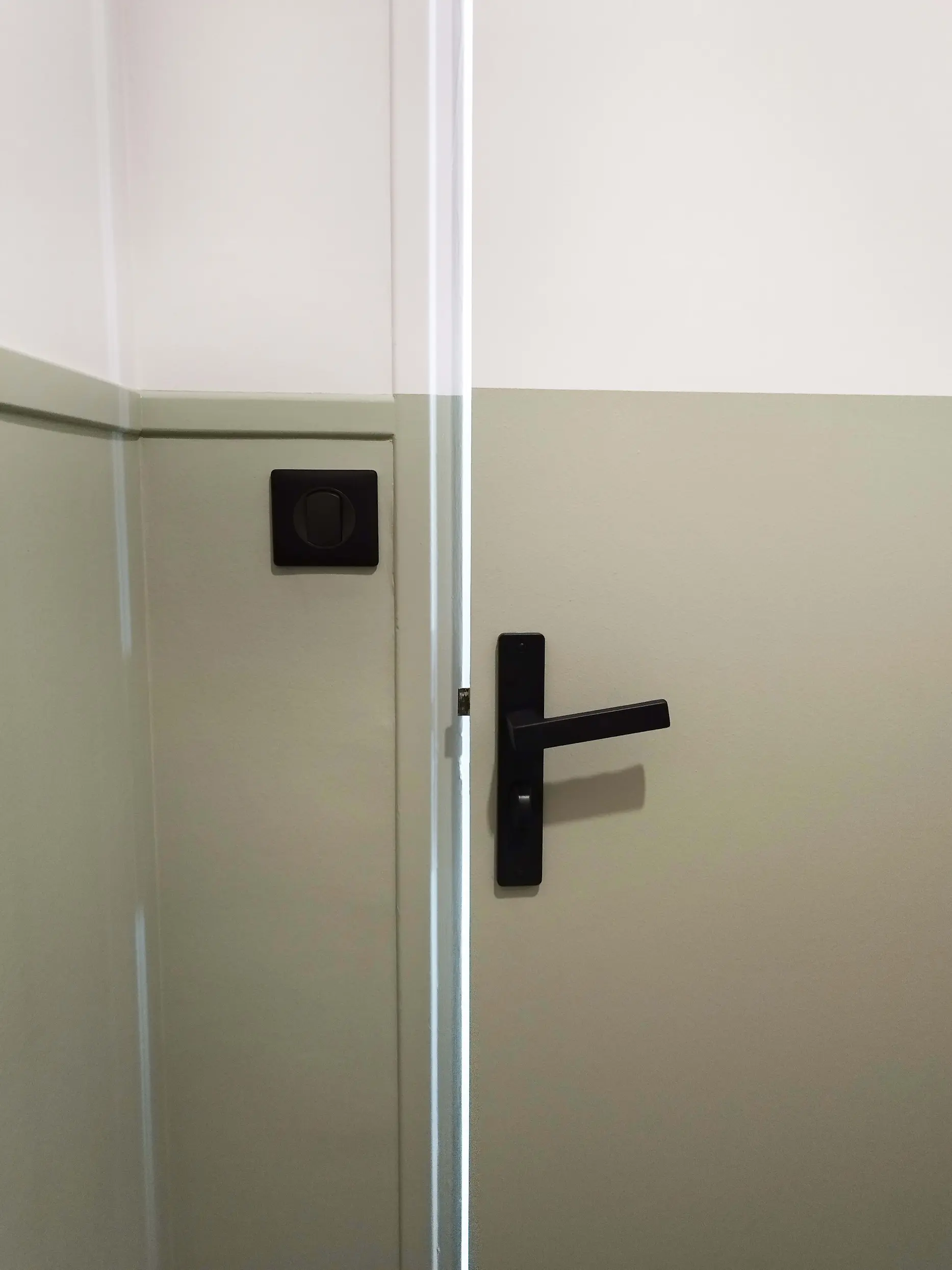Gros plan sur une poignée de porte noire, élément de la rénovation de l’appartement.