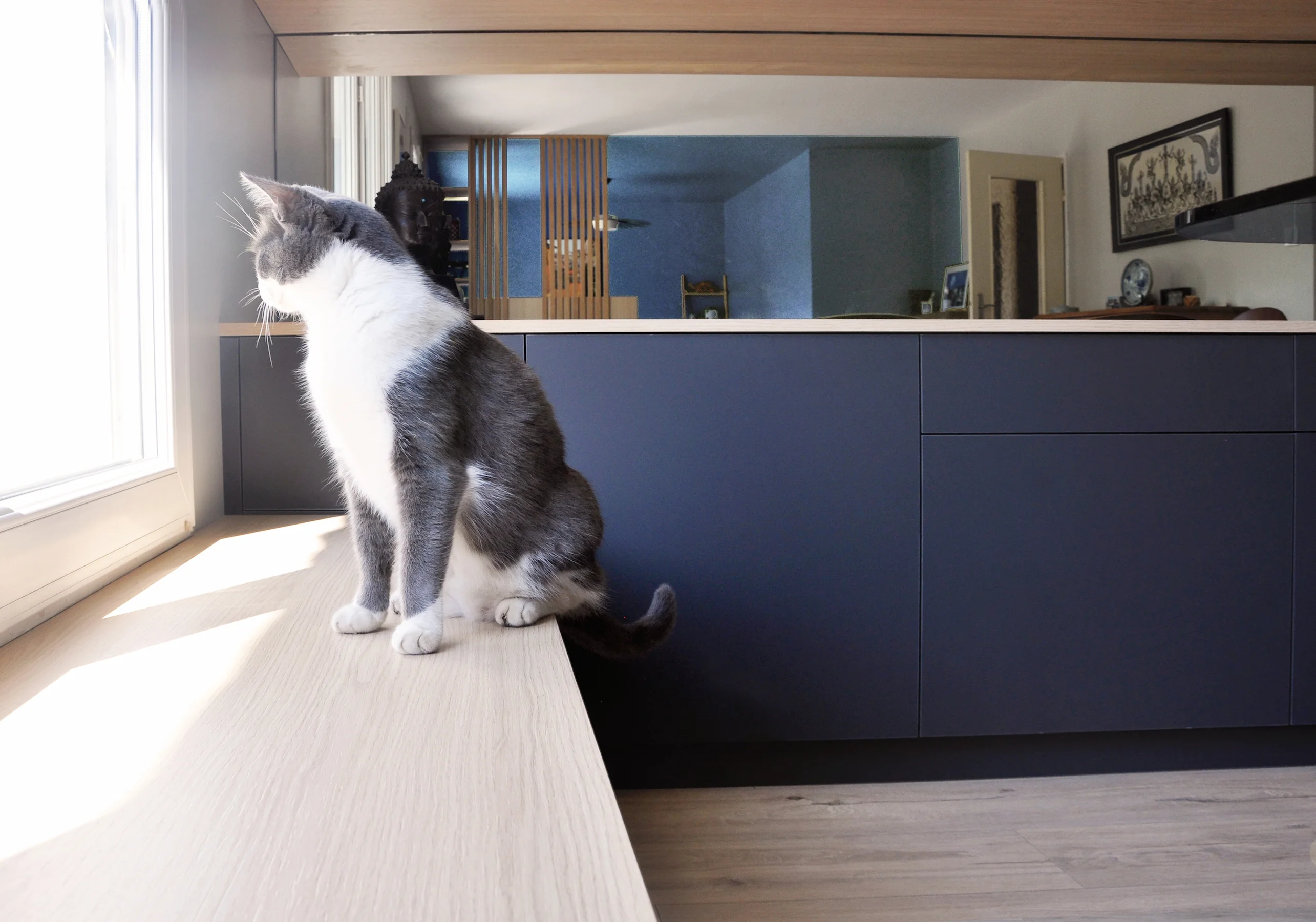 Meuble bas sur mesure servant d’assise près de la fenêtre, dans une pièce de vie réorganisée.