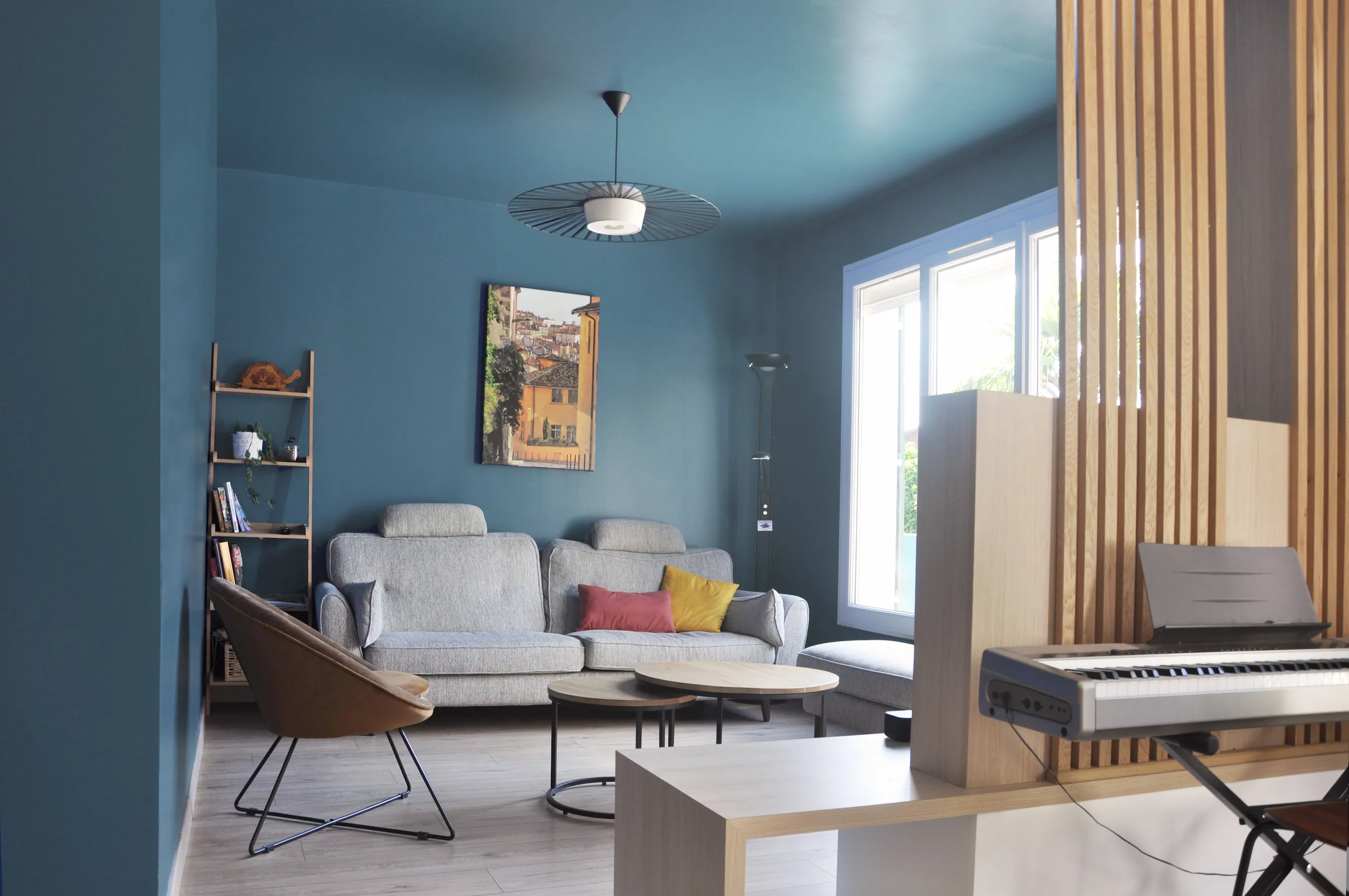 Vue d’ensemble de la pièce de vie avec claustra bois et mobilier sur mesure.