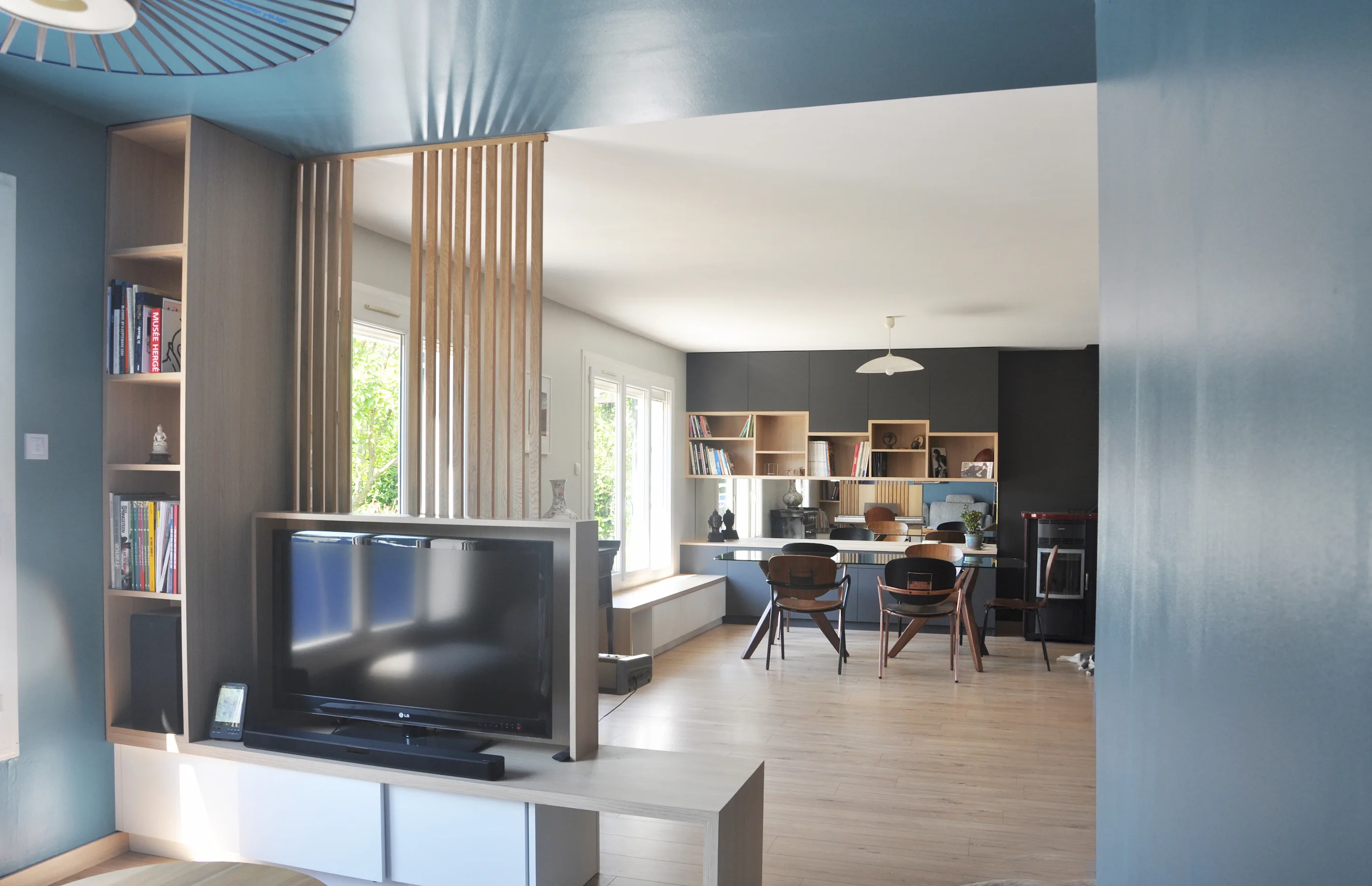 Vue de la pièce de vie réaménagée avec des meubles sur mesure : meuble TV séparatif, claustras en bois, imaginé par l'agence Jiwa.a