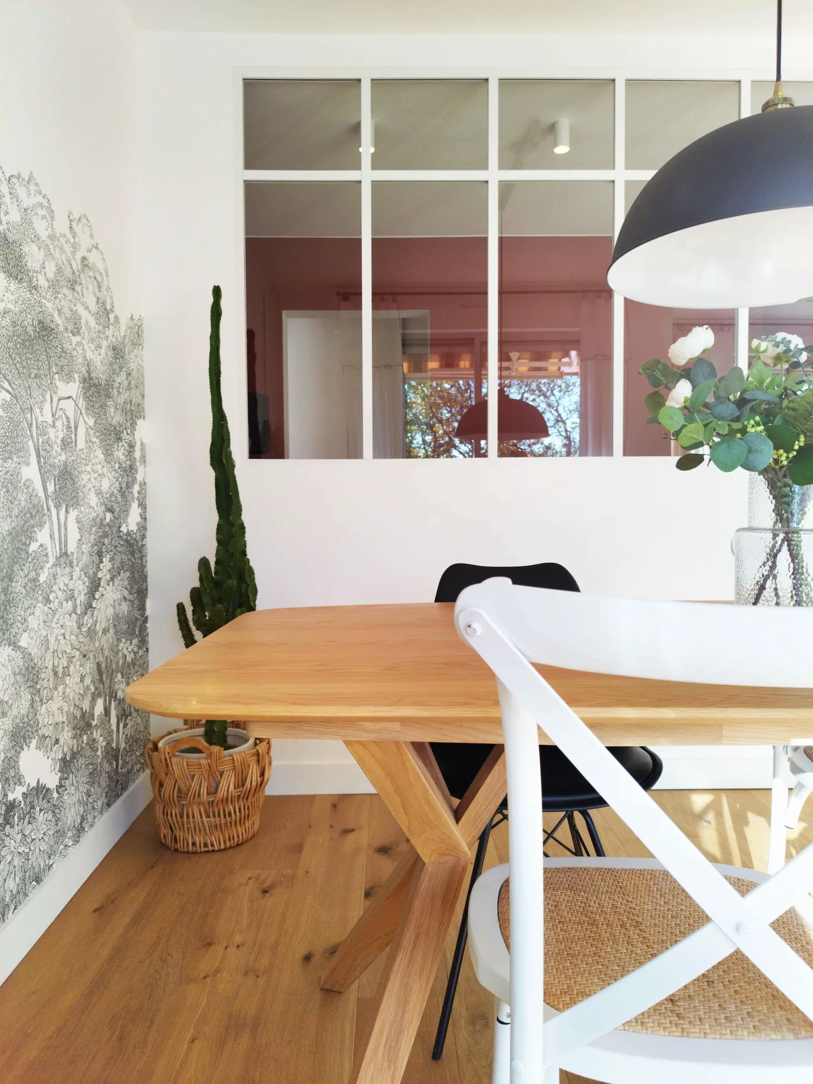 Détail de la salle à manger avec verrière blanche, table en bois et décoration végétale, projet de réhabilitation par Valentine Bourdier architecte d’intérieur.