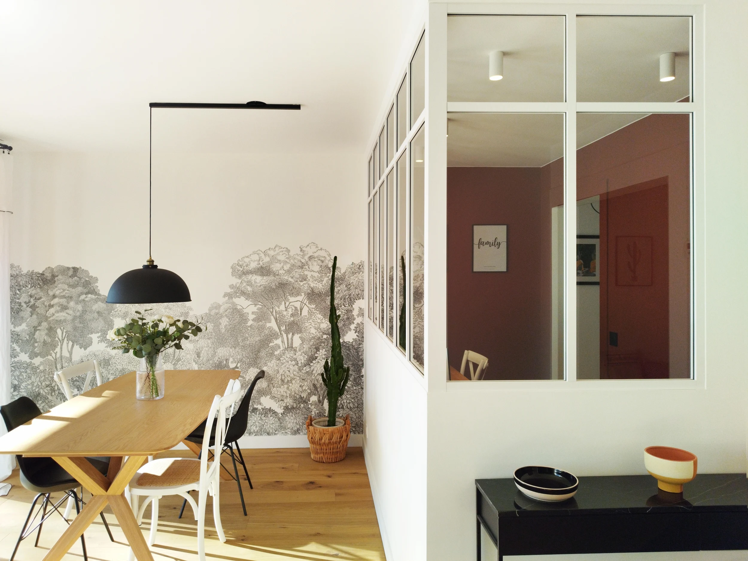 Espace salle à manger avec table en bois et verrière intérieure.