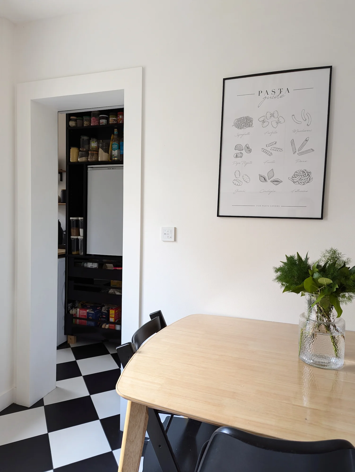 Table à manger en bois clair avec vue sur un cellier optimisé, intégrant rangements et électroménager, dans un appartement réhabilité à Lyon.