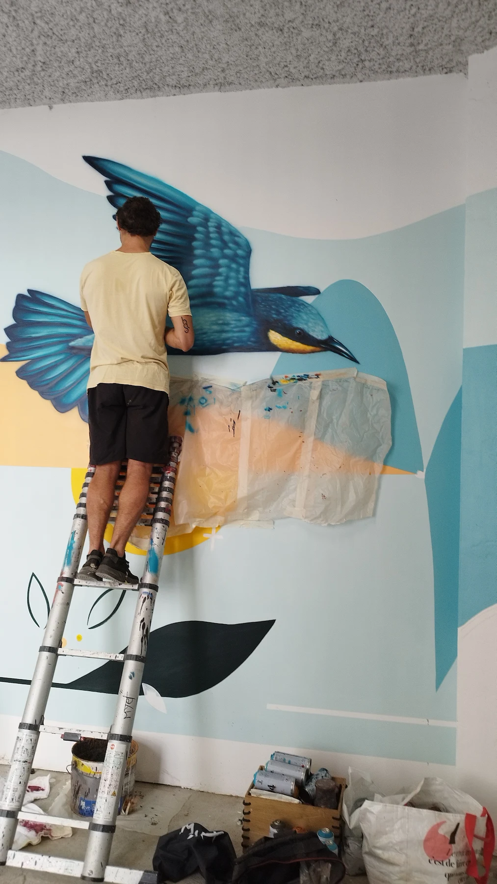 Artiste réalisant une fresque murale, intervention de peinture urbaine dans un local vélo à Lyon.