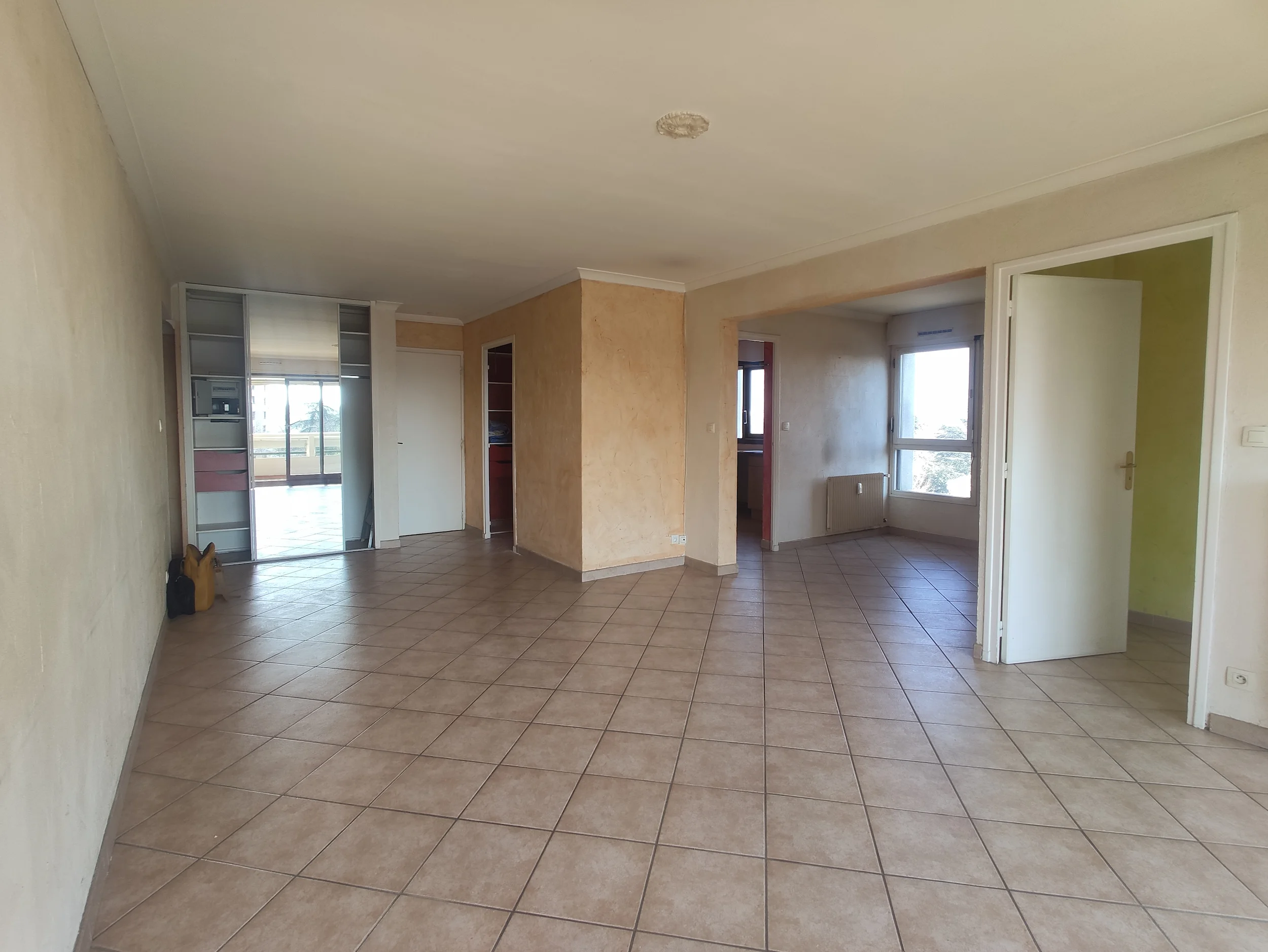 Séjour avant travaux avec sol carrelé et cloisons existantes dans un appartement