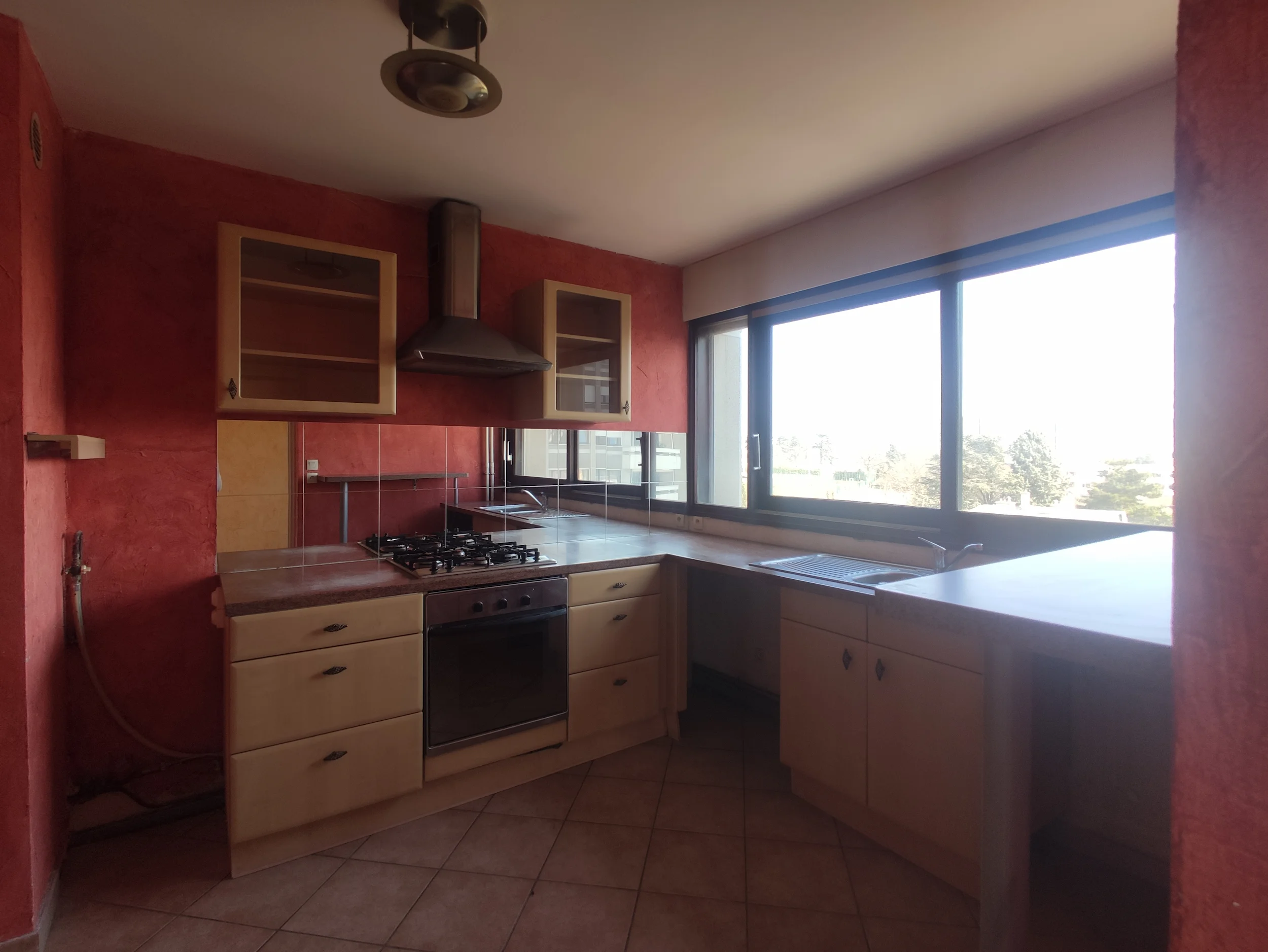 Cuisine avant rénovation avec meubles existants et carrelage au sol.