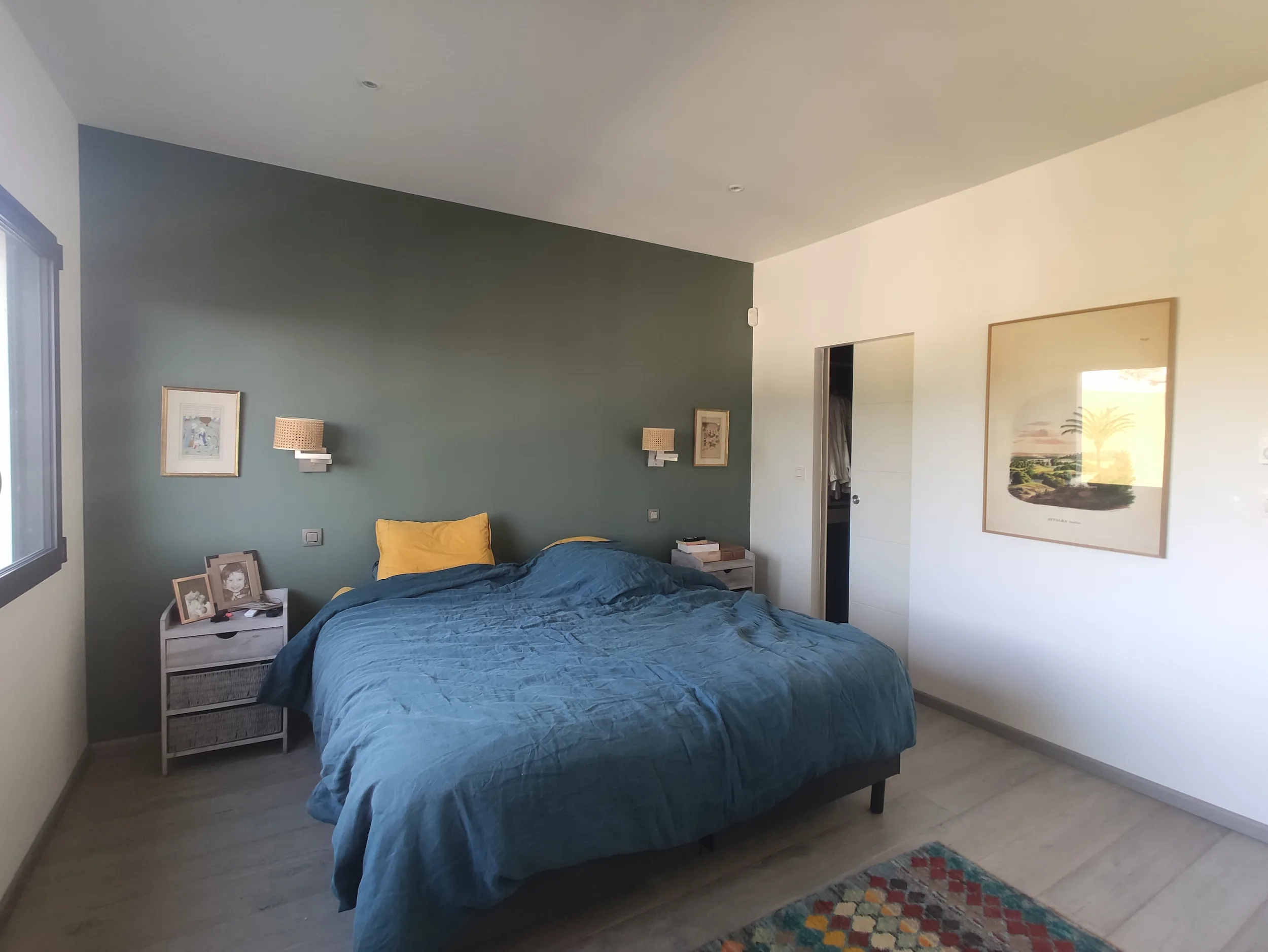 Chambre avant travaux avec lit double, mur peint vert foncé et mobilier existant