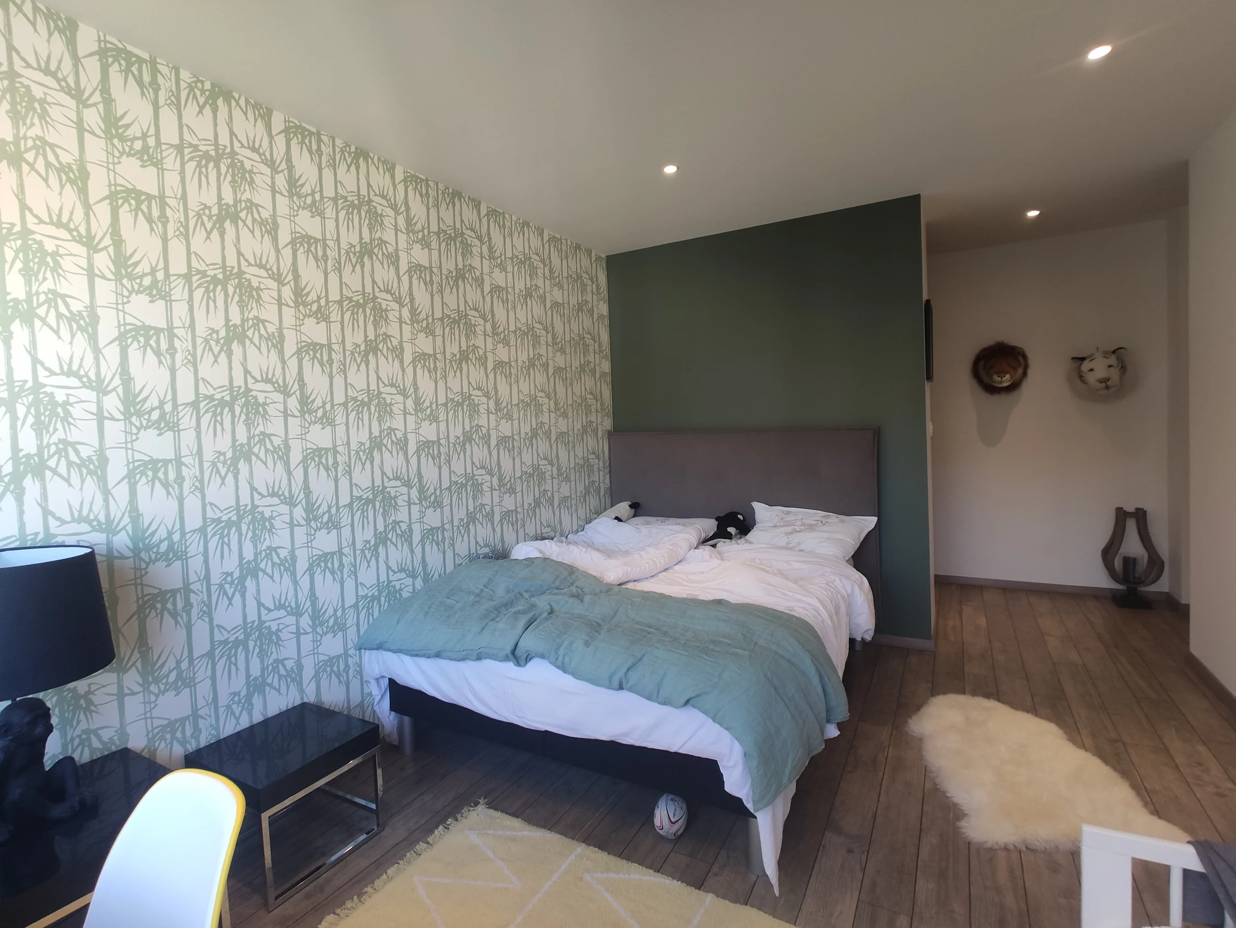 Chambre avant travaux avec papier peint végétal, lit et sol en bois apparent