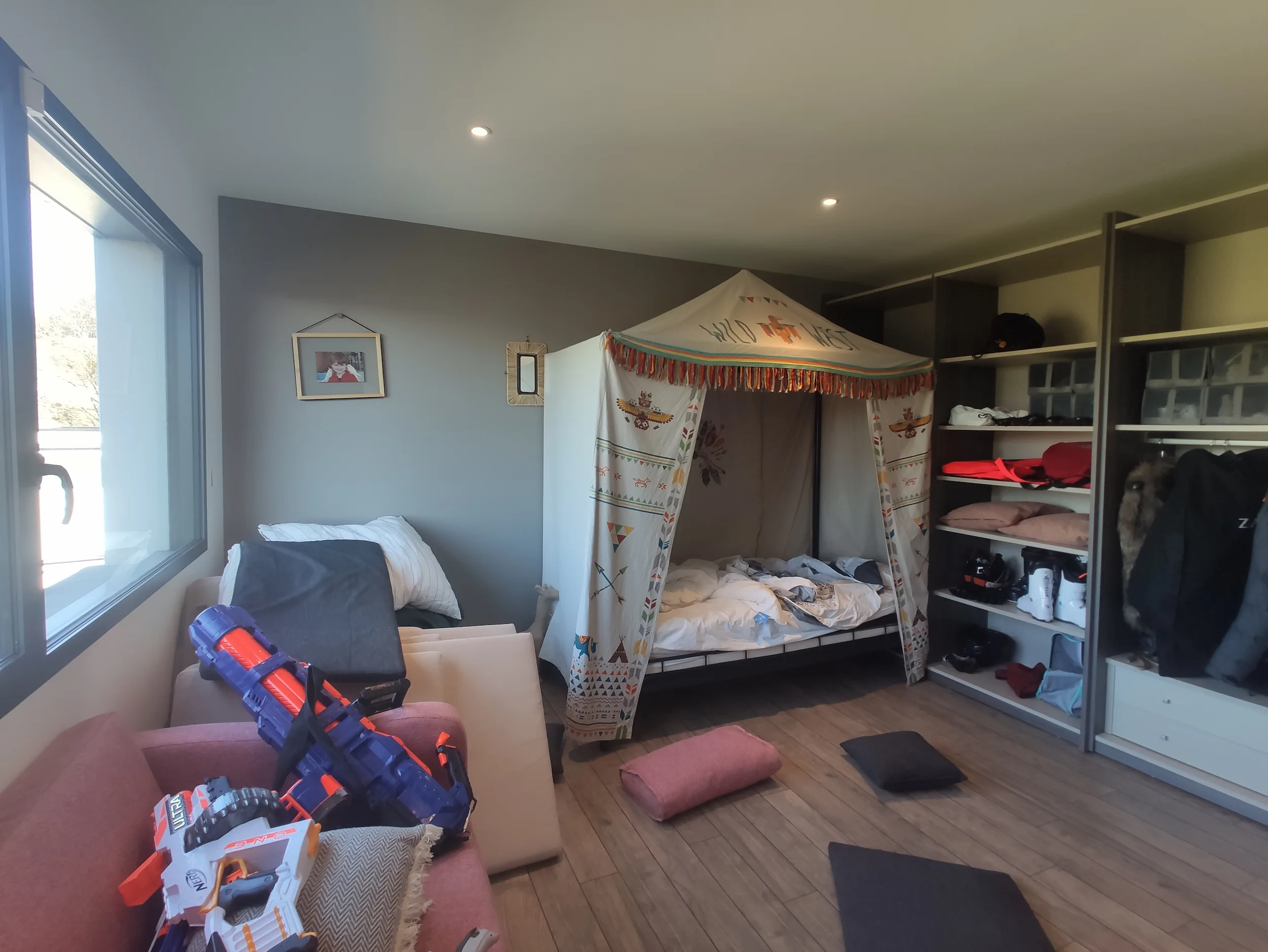 Chambre avant travaux avec espace enfant, tente de jeu et rangements ouverts