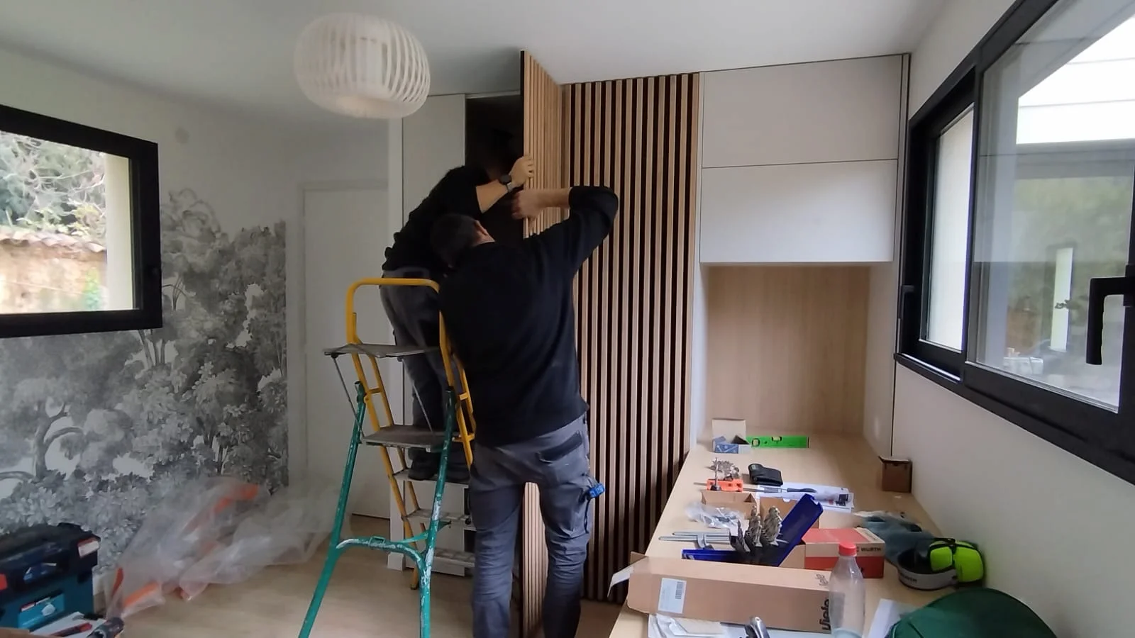 Intérieur de l’extension avant travaux, espace brut avec cloisons et mobilier en cours d’installation.