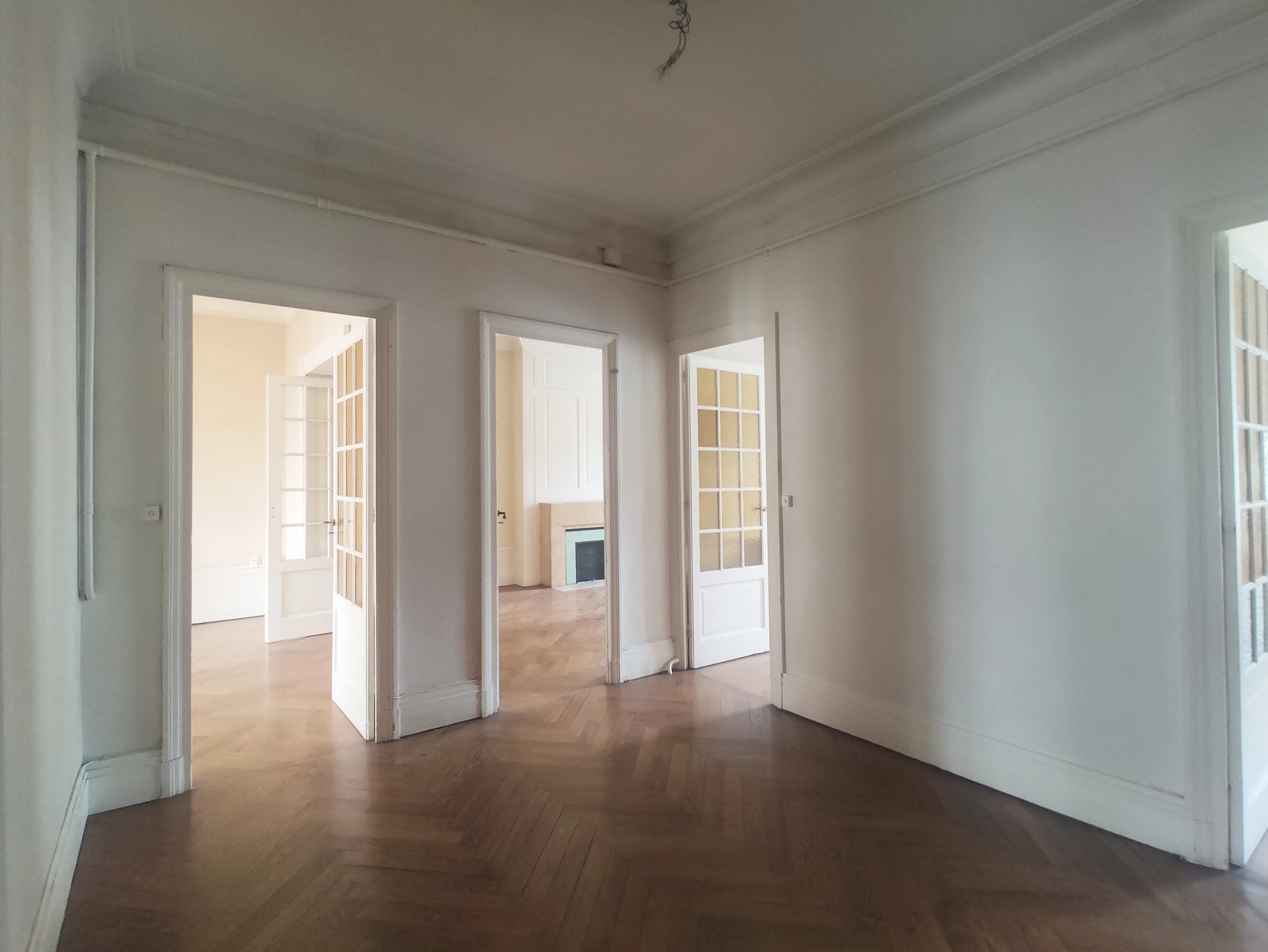 Salon d’appartement lyonnais avant travaux, parquet ancien et moulures d’origine.