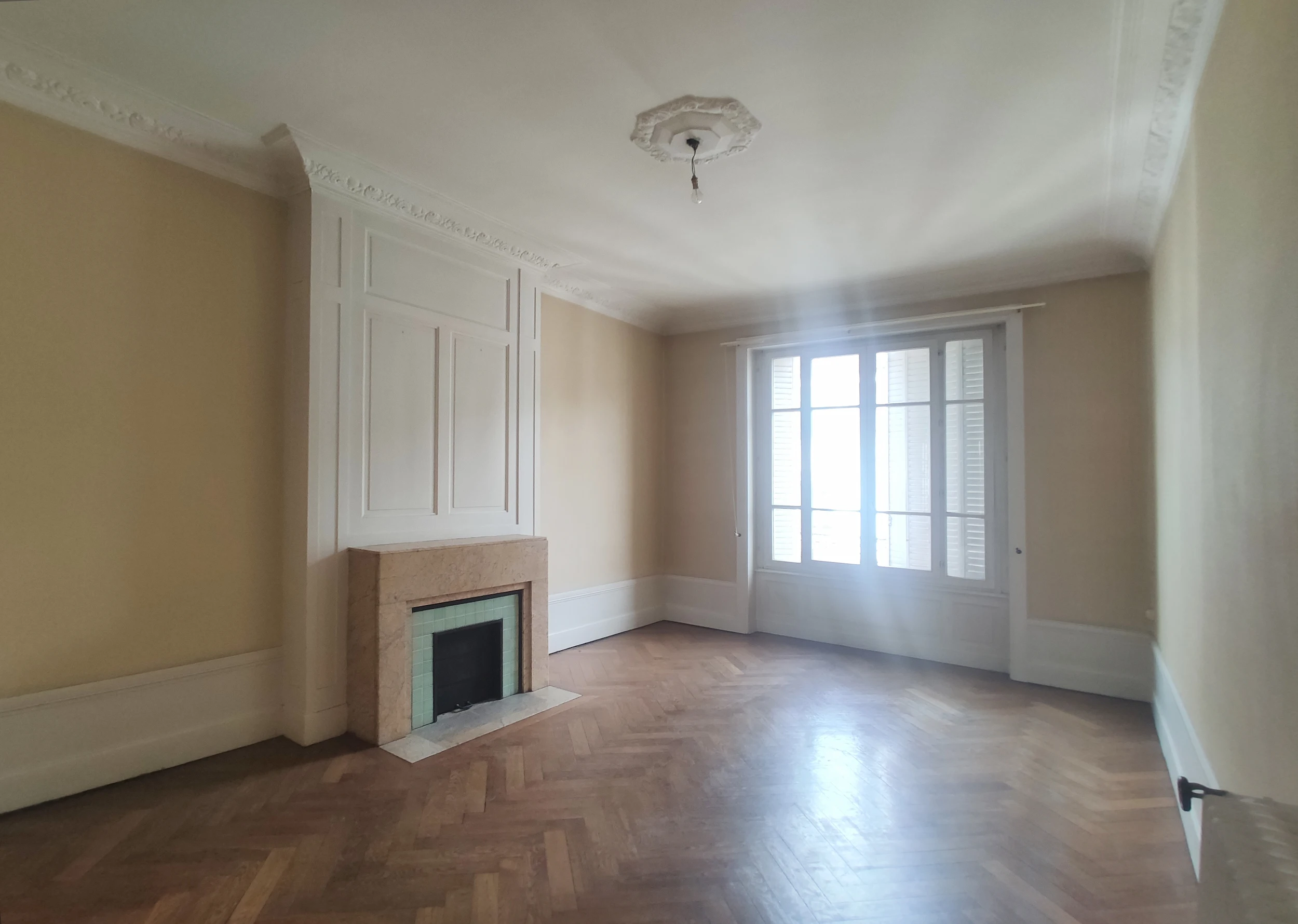 Séjour avant réhabilitation avec cheminée, parquet chevrons et hauteur sous plafond.