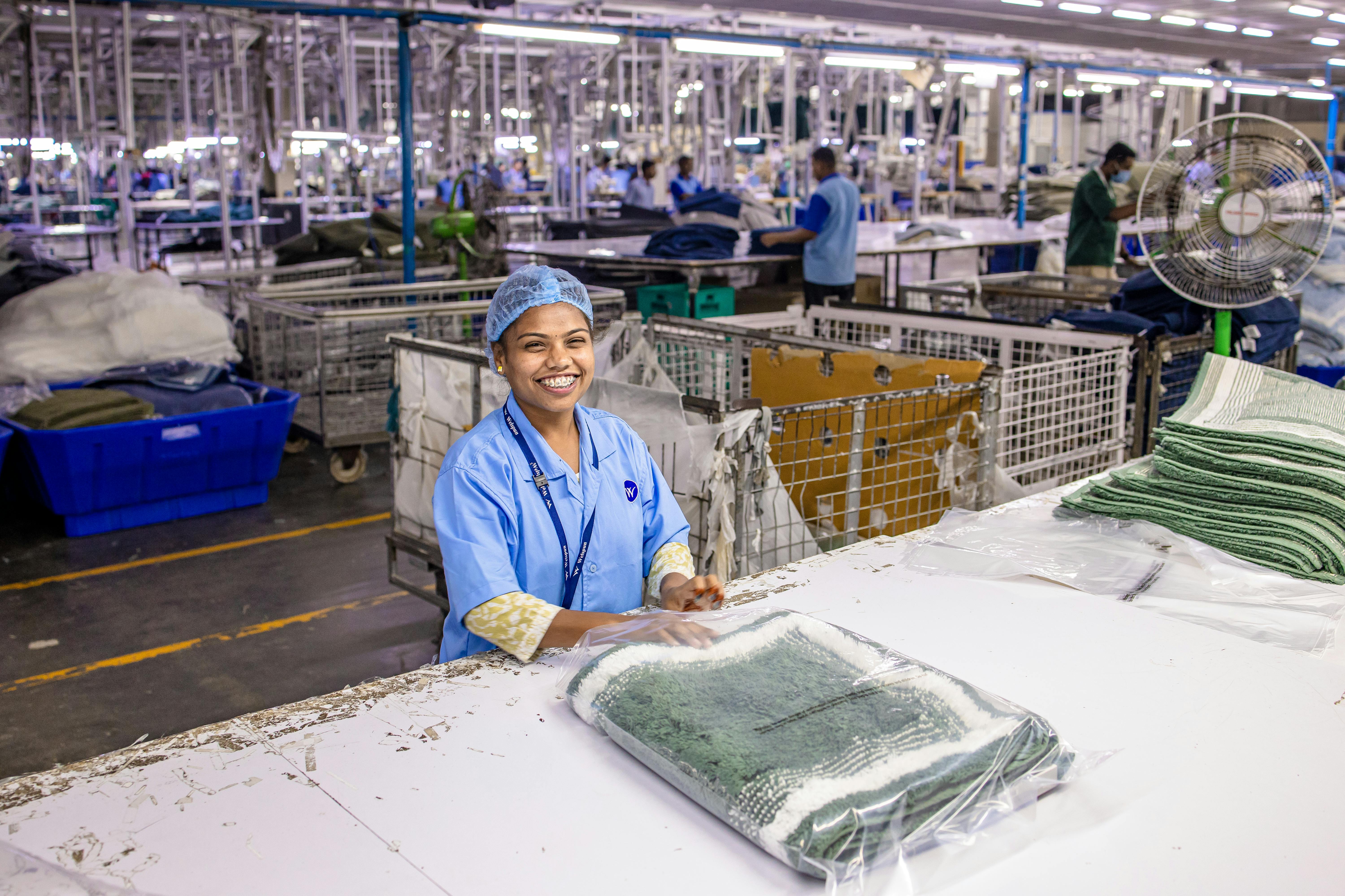 A textile operator with packing up finished goods for shipment with other assemblies in the background of warehouse