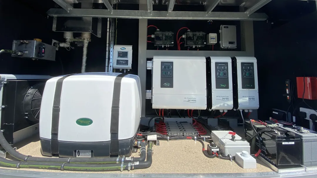 Electrical system setup featuring WhisperPower branded components including an AC PowerCube and two WP-DC PowerCubes connected with red and black cables inside a metal enclosure.