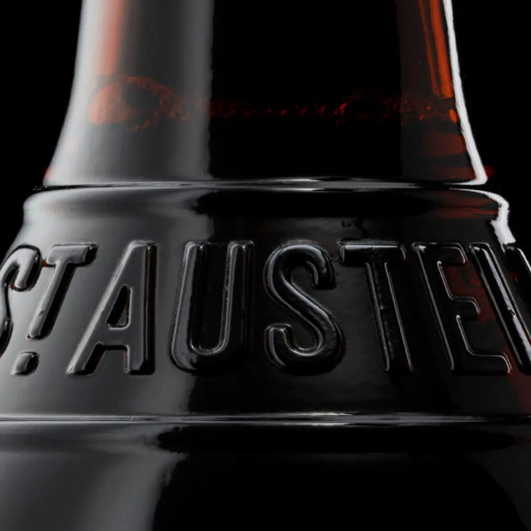 Close-up of a dark bottle neck with embossed letters spelling ‘ST AUSTEL’.