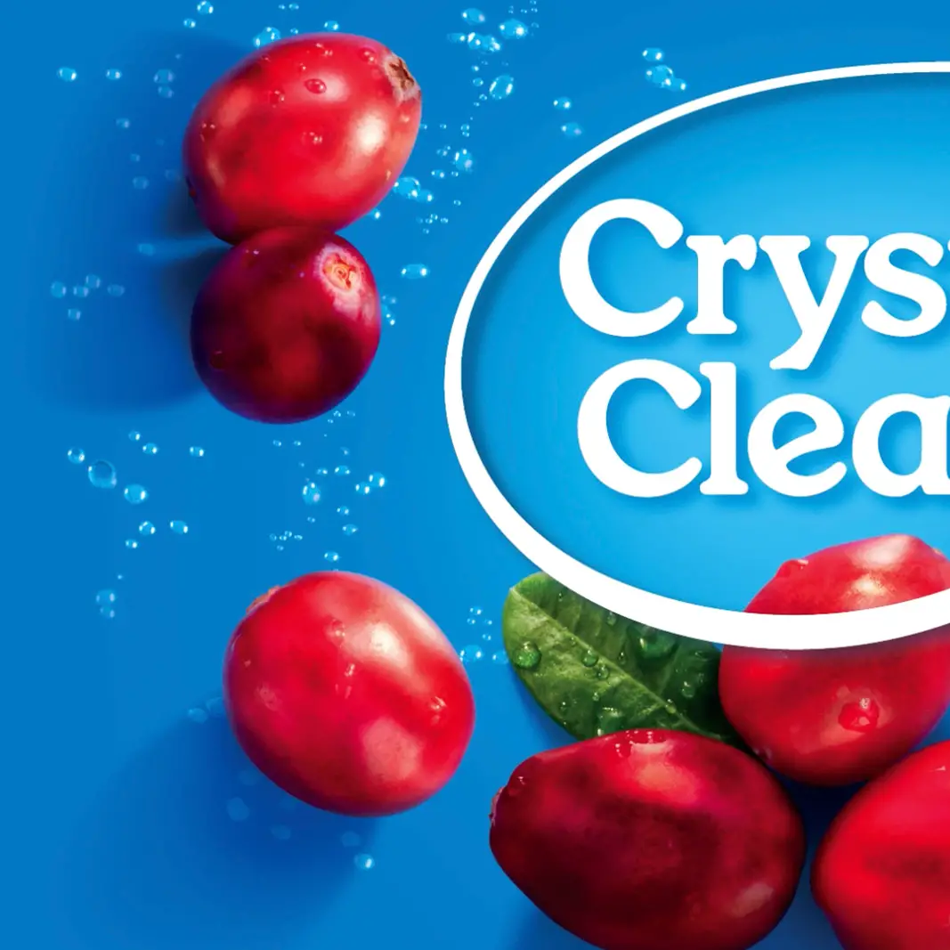 Close-up of red cranberries and green leaf against a blue background with part of the text 'Crystal Clear'.