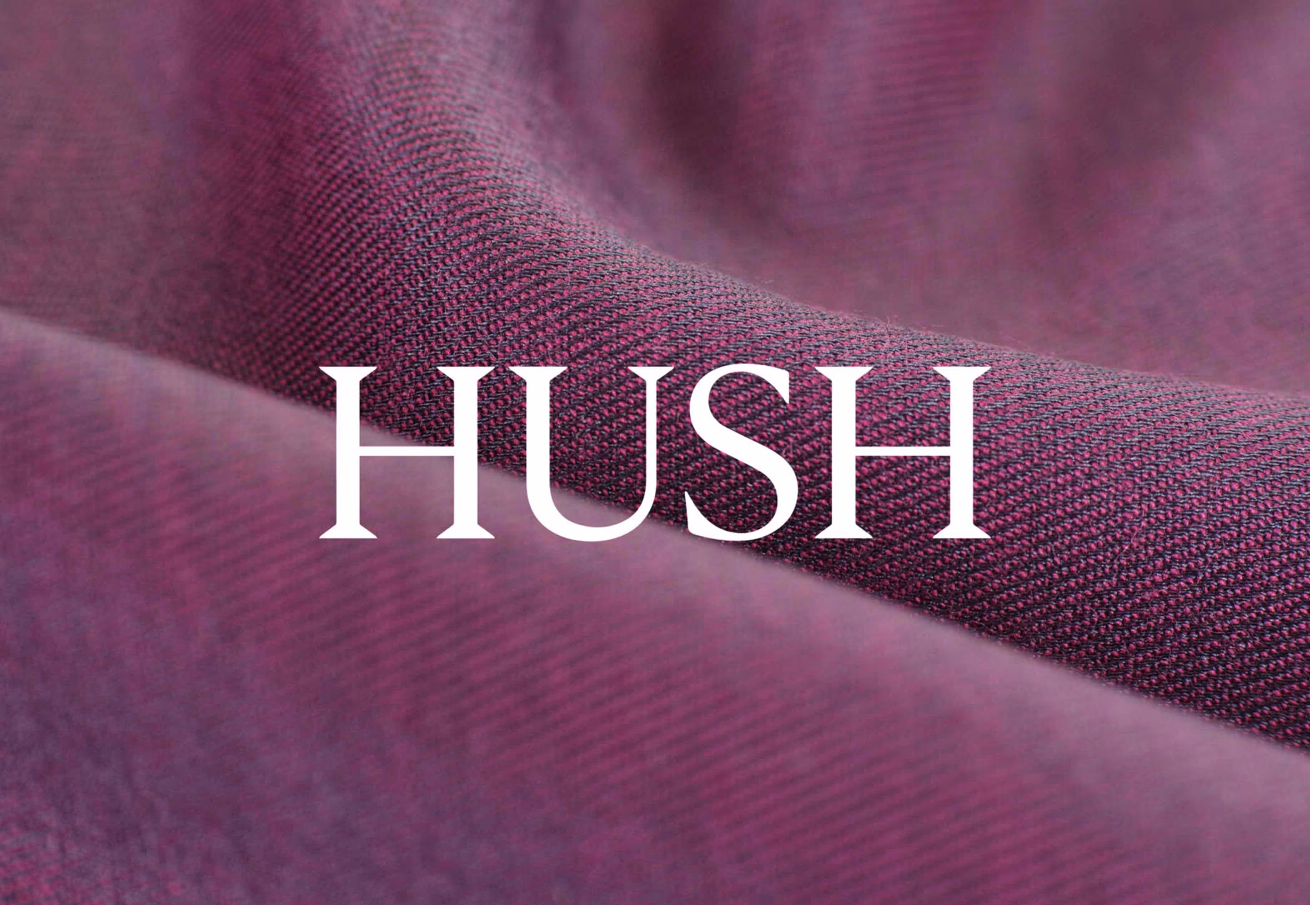 Close-up of textured purple fabric with the word HUSH in white capital letters across the center.