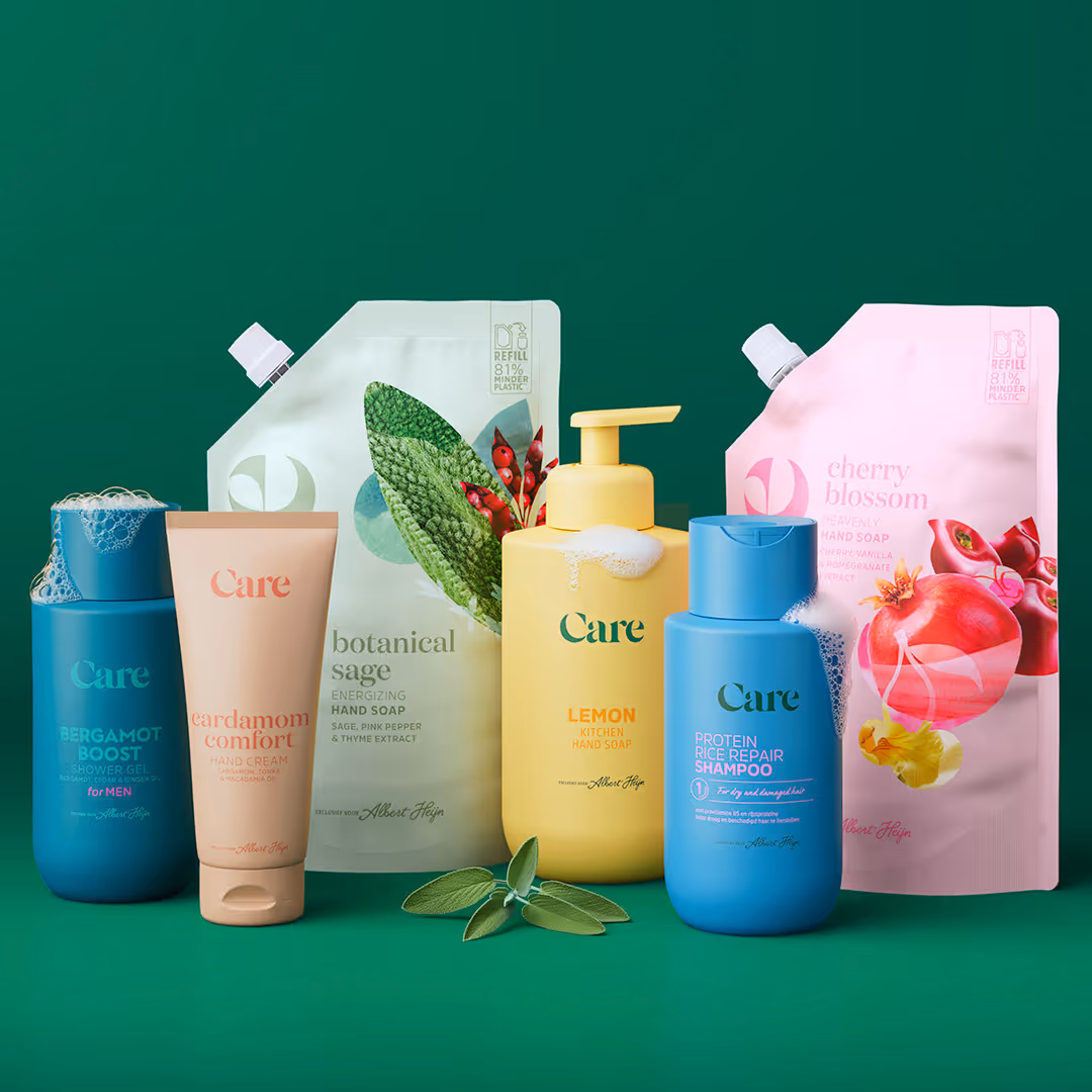 Various Care brand personal care products including bergamot shower gel, cardamom hand cream, botanical sage hand soap refill, lemon kitchen hand soap, protein rice repair shampoo, and cherry blossom hand soap refill arranged on green background.