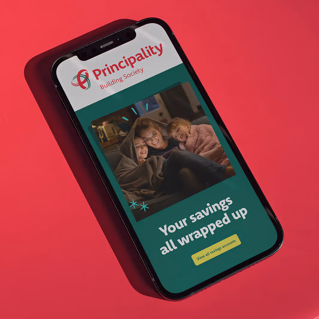 Smartphone displaying Principality Building Society ad with a family wrapped in blankets and text 'Your savings all wrapped up.'