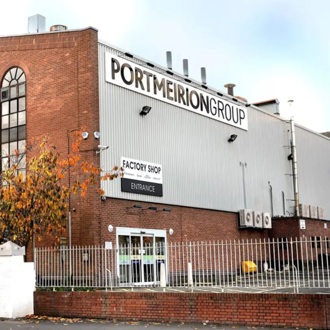 Brick and metal factory building with sign reading 'Portmeirion Group' and entrance to factory shop.