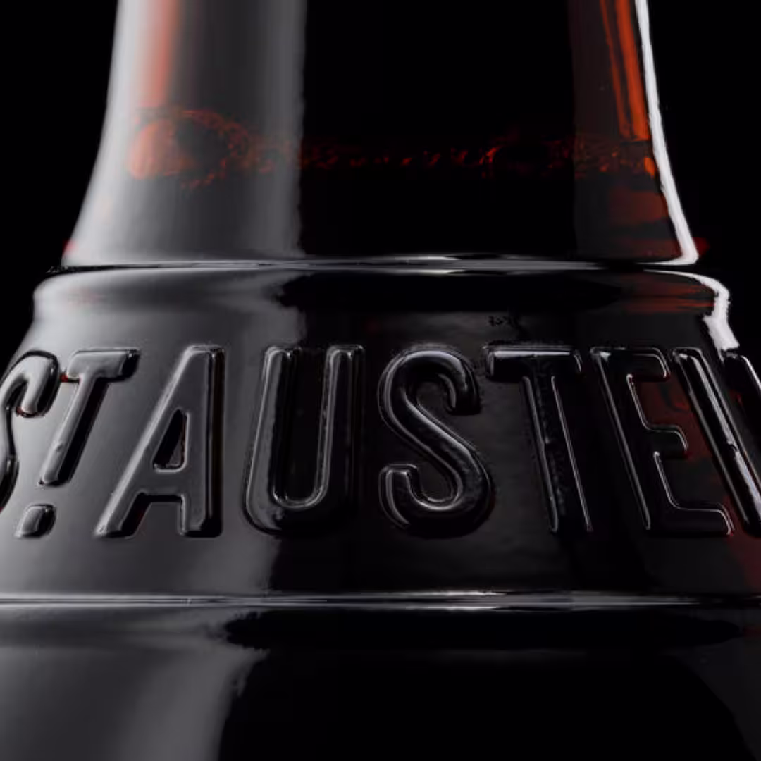Close-up of a dark glass bottle neck with the embossed word 'ST AUSTEL'.