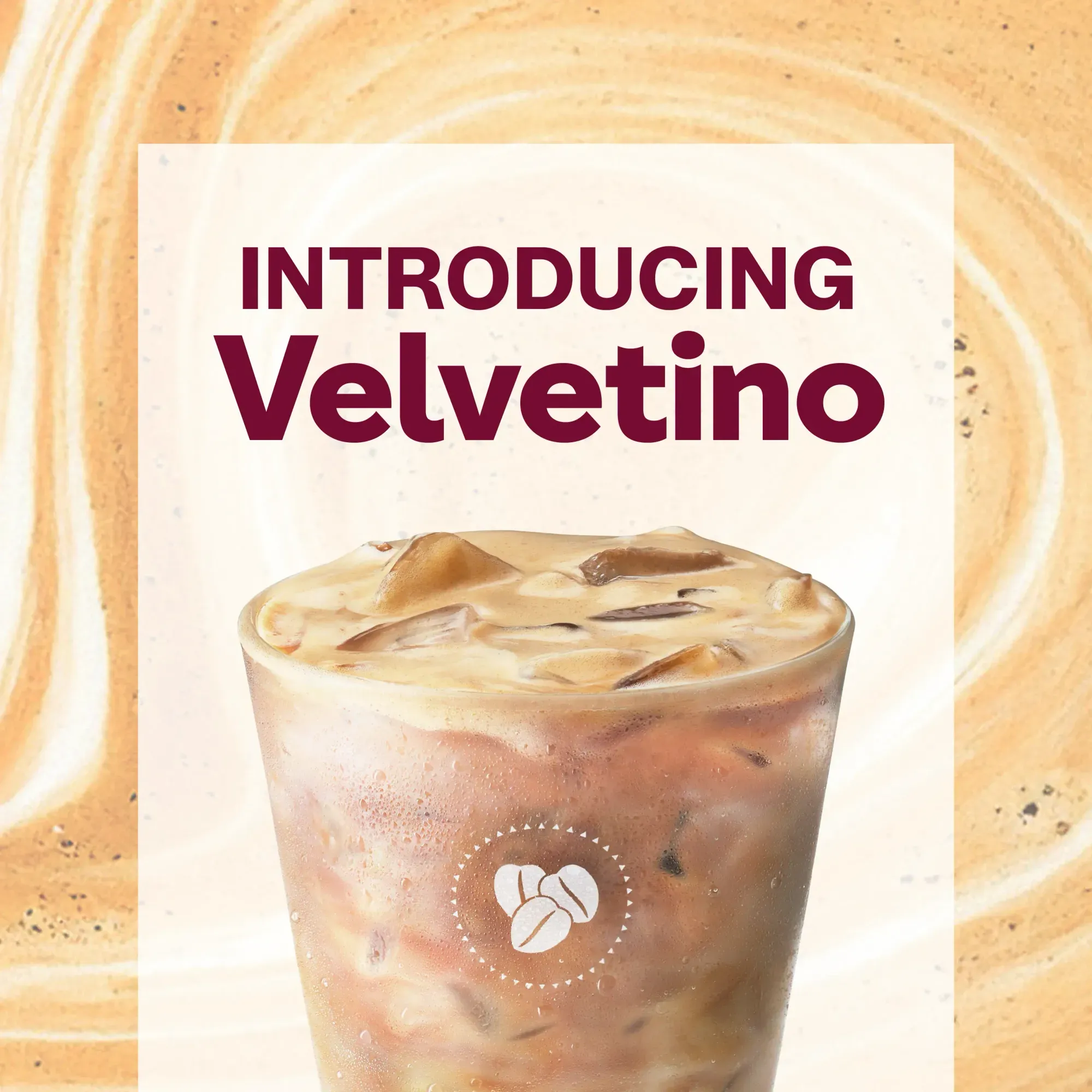 Iced coffee drink named Velvetino with creamy layers and coffee bean icon on cup.