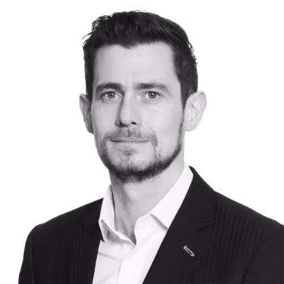Black and white portrait of a man with short hair and beard wearing a suit and white shirt.