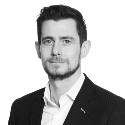 Black and white portrait of a man with short hair and beard wearing a suit and white shirt.