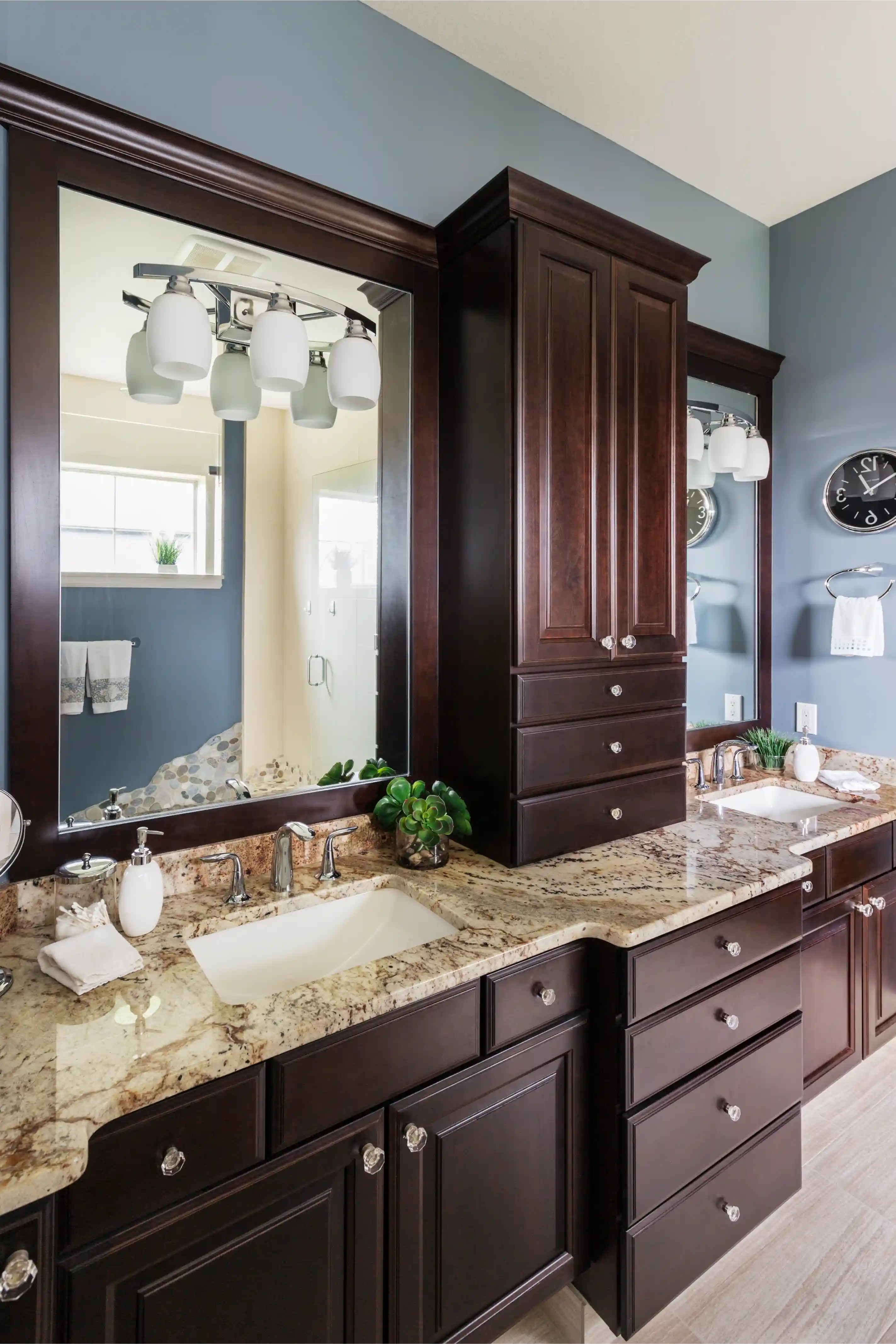Modern bathroom with double sink vanity featuring dark wood cabinets and granite countertops under large mirrors.