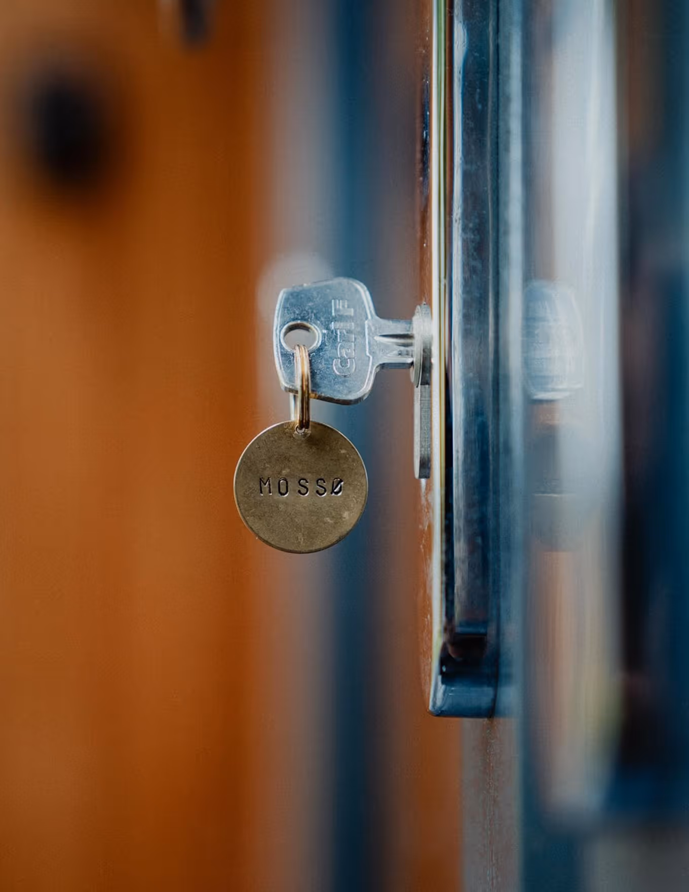 Close-up of a key inserted in a metal lock with a round brass keychain engraved with 'MOSSO'.