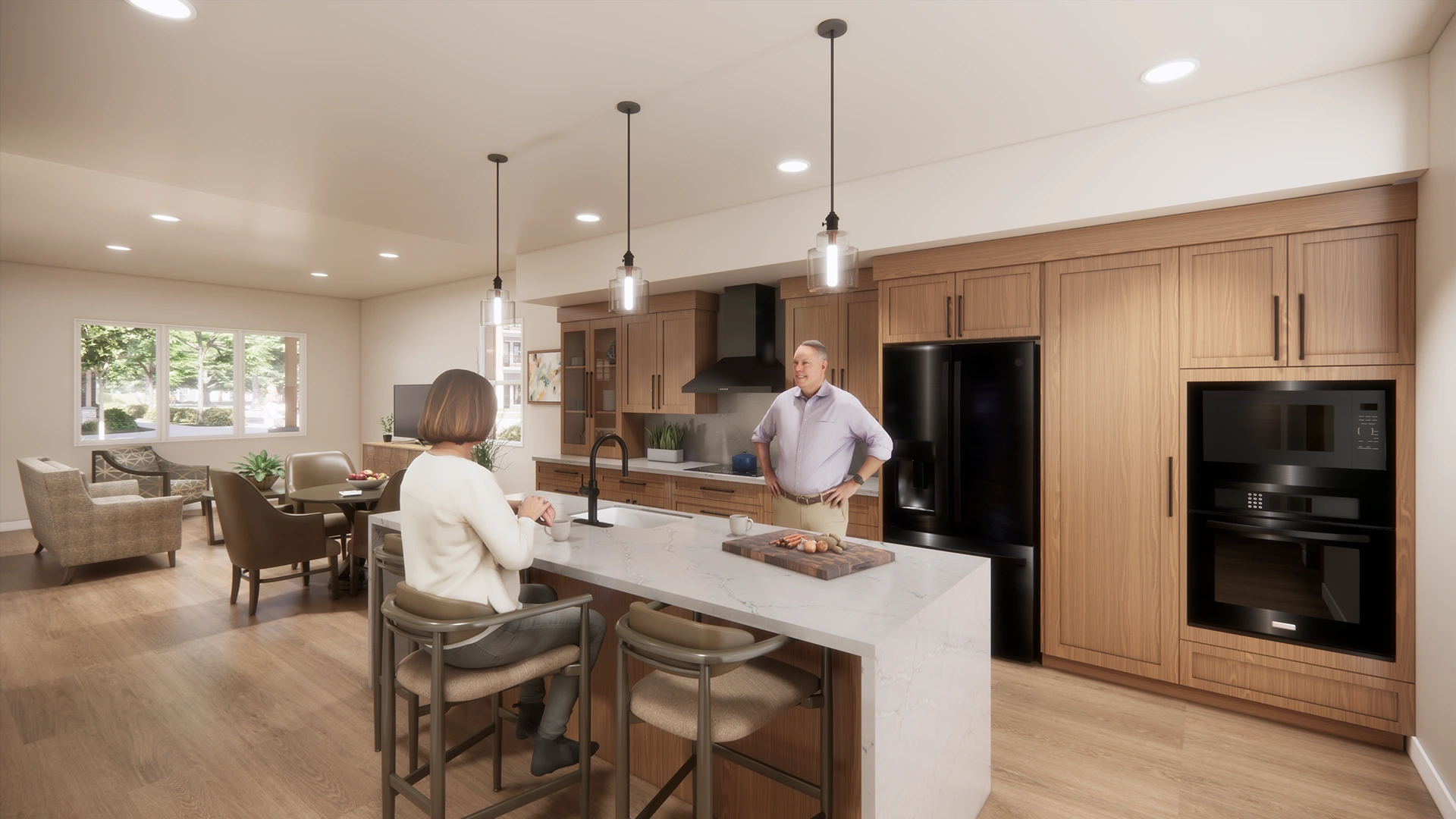 Modern open kitchen and living area with wooden cabinets, a large white island, two people conversing, and pendant lights overhead.