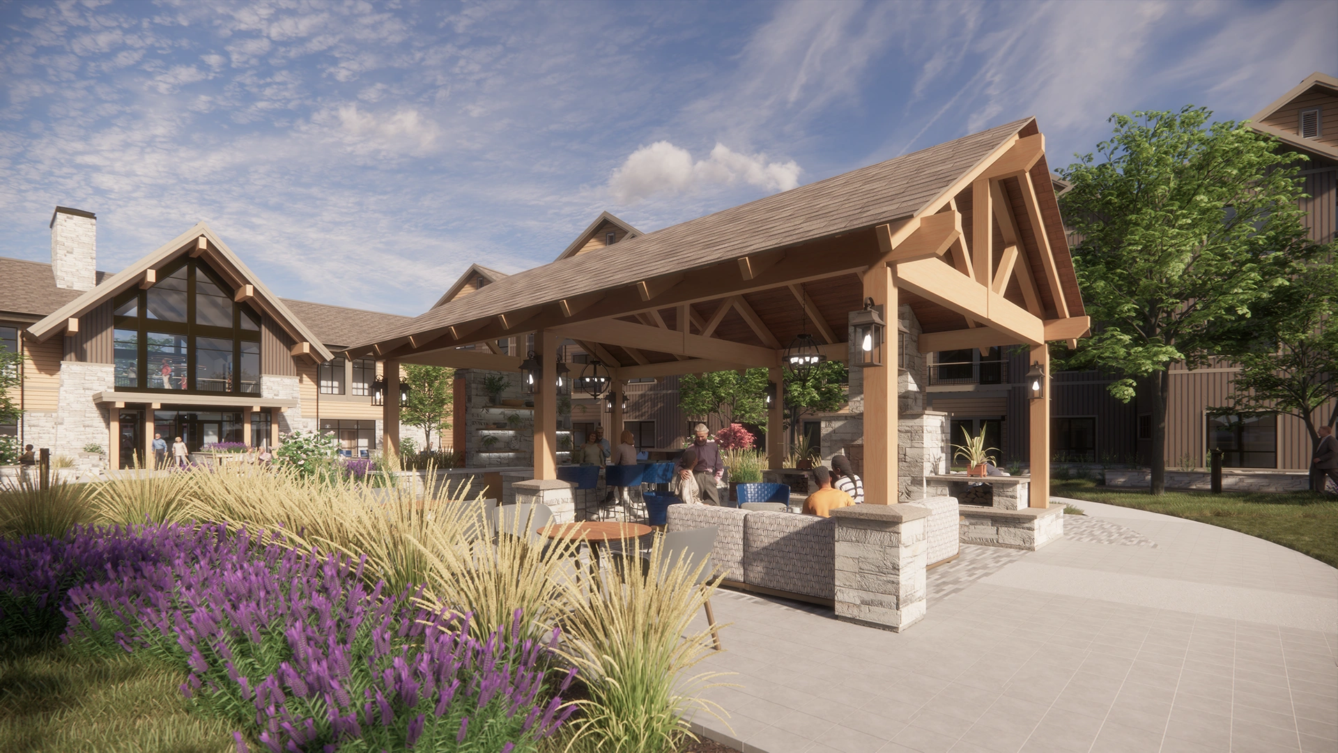 Outdoor pavilion with wooden beams and stone pillars featuring seating and people socializing near a multi-story building with large windows.