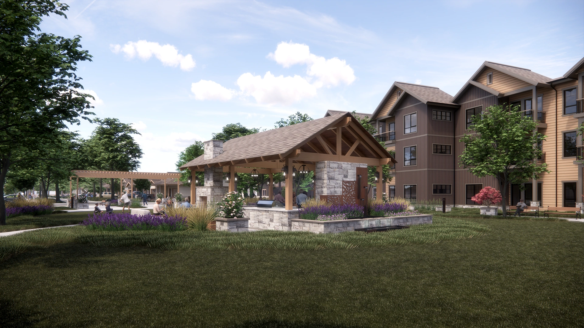 Outdoor pavilion with stone and wood structure surrounded by green lawn, purple flowers, and apartment buildings in the background.