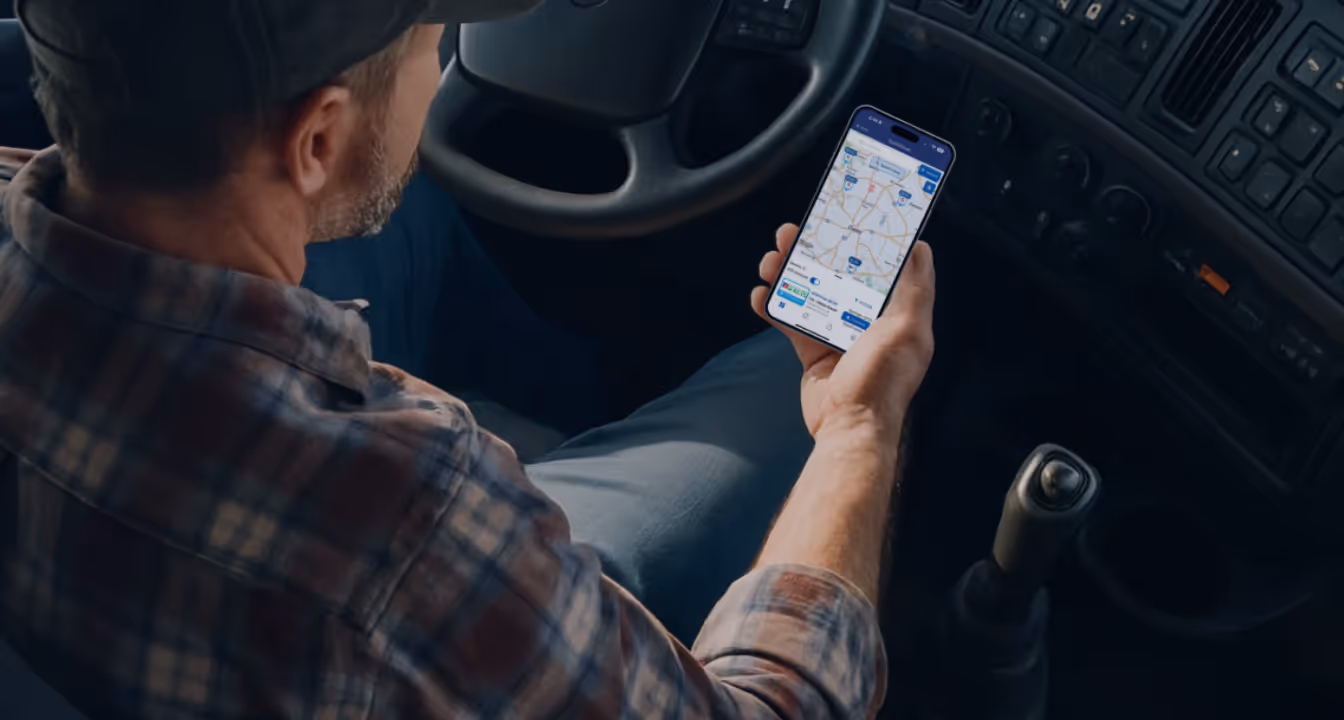 Trucker using smartphone app to find the cheapest diesel fuel prices while sitting in the cab of a truck.