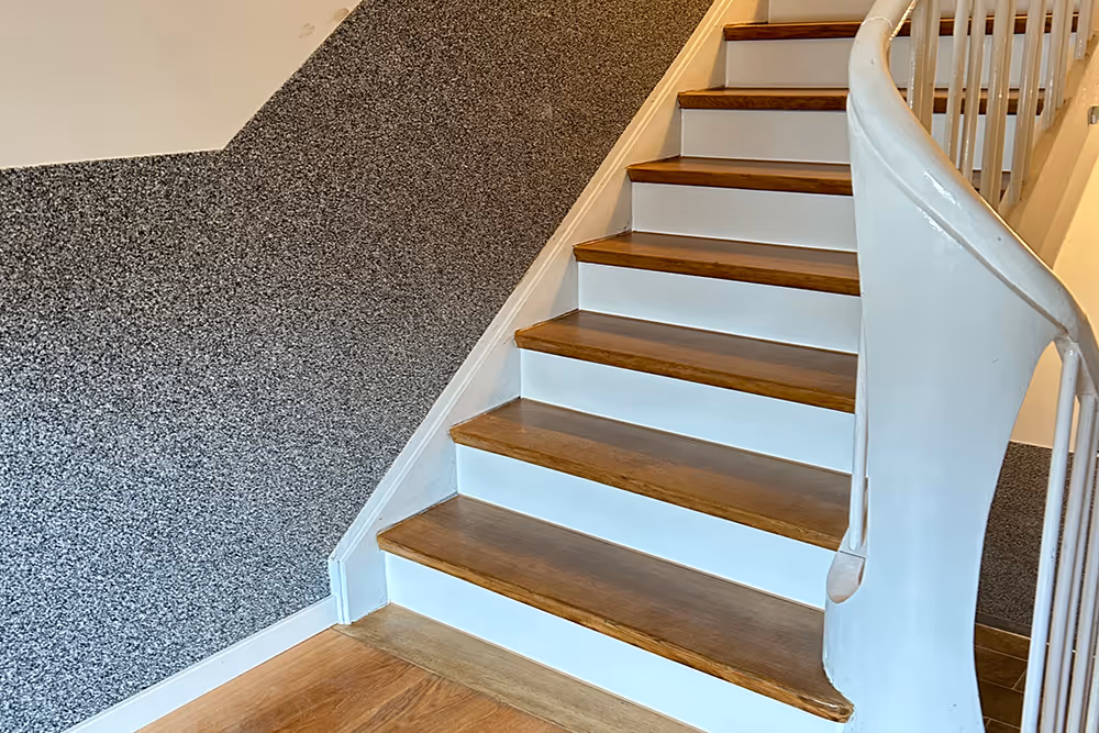 Innenaufnahme einer Holztreppe mit weißen Stufenwangen und einer weißen, geschwungenen Treppengeländer.