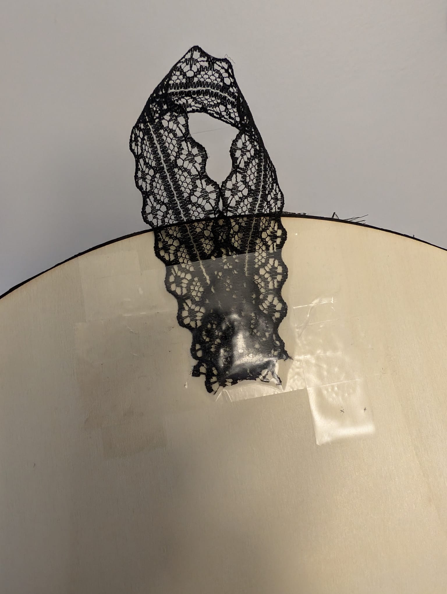 A loop of black ribbon taped to the back of the wooden disc