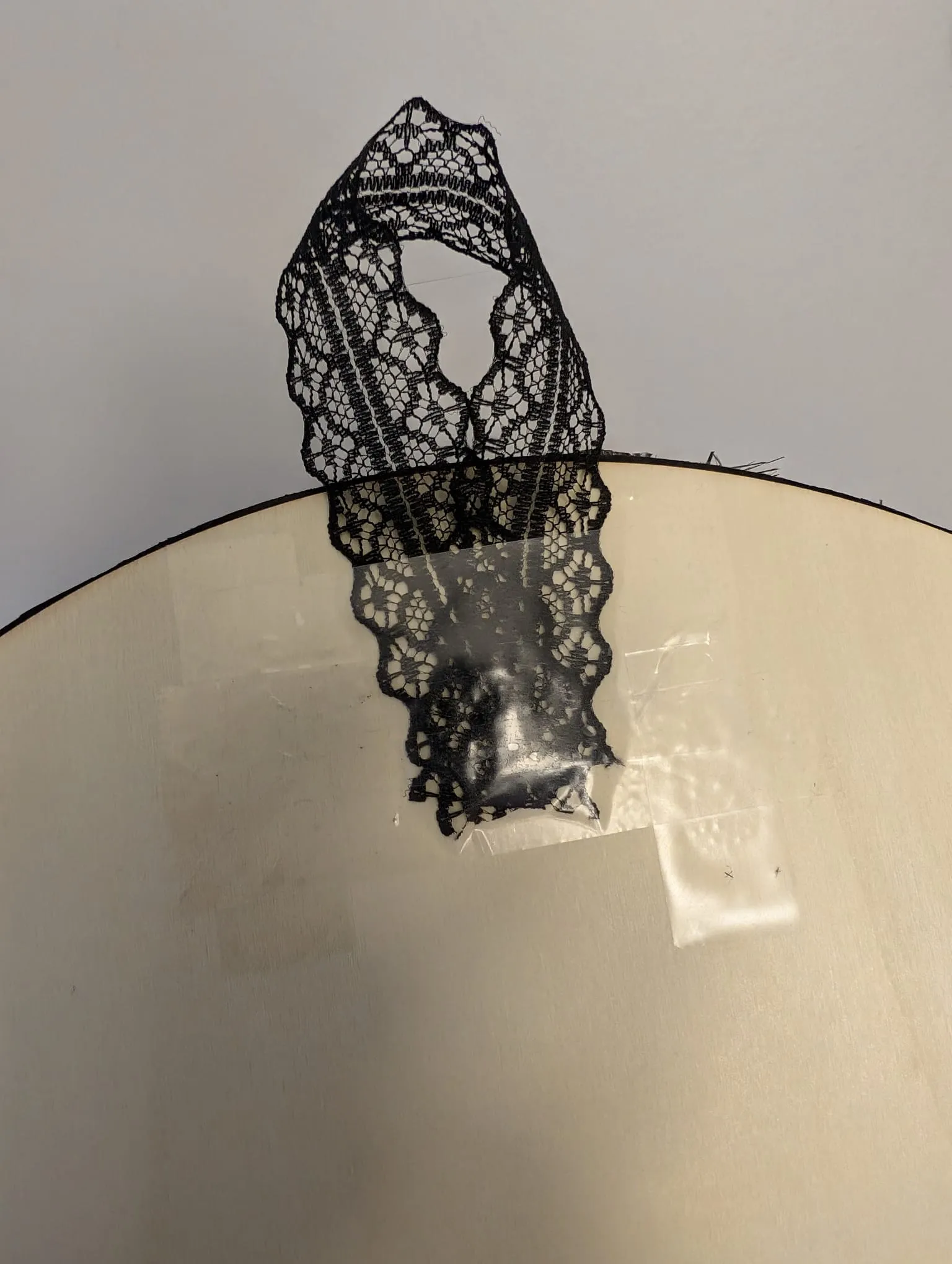 A loop of black ribbon taped to the back of the wooden disc