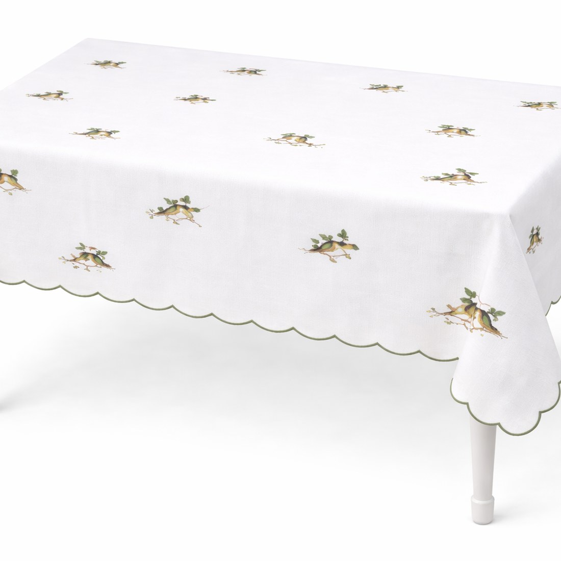 Green scalloped-edge tablecloth printed with small bird-and-branch motifs, on a dining table