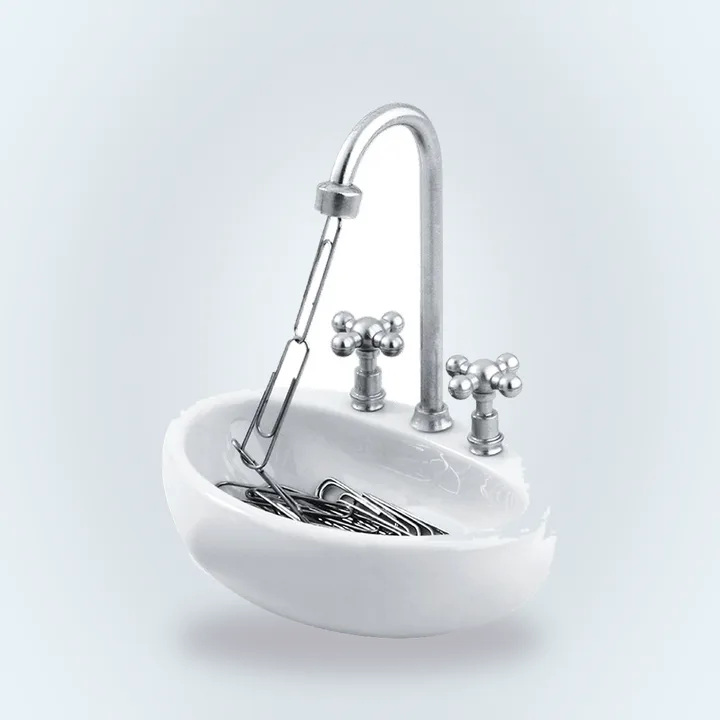 Miniature white kitchen sink holding paper clips