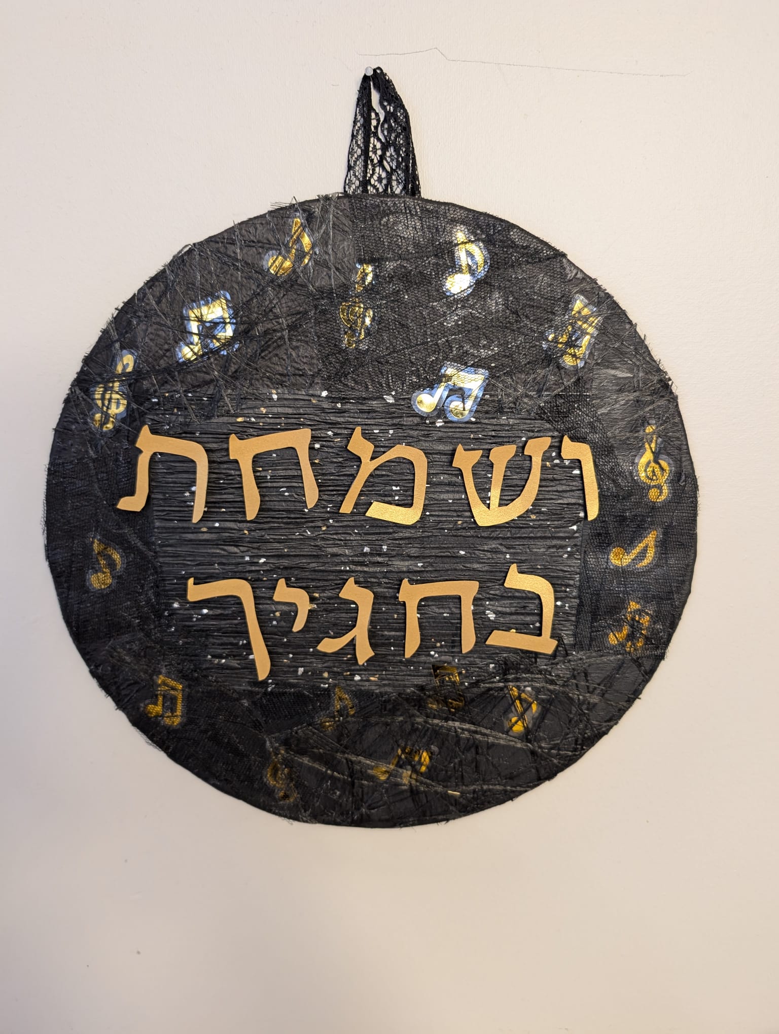 Round black-and-gold decoupage sukkah sign reading V'samachta B'chagecha