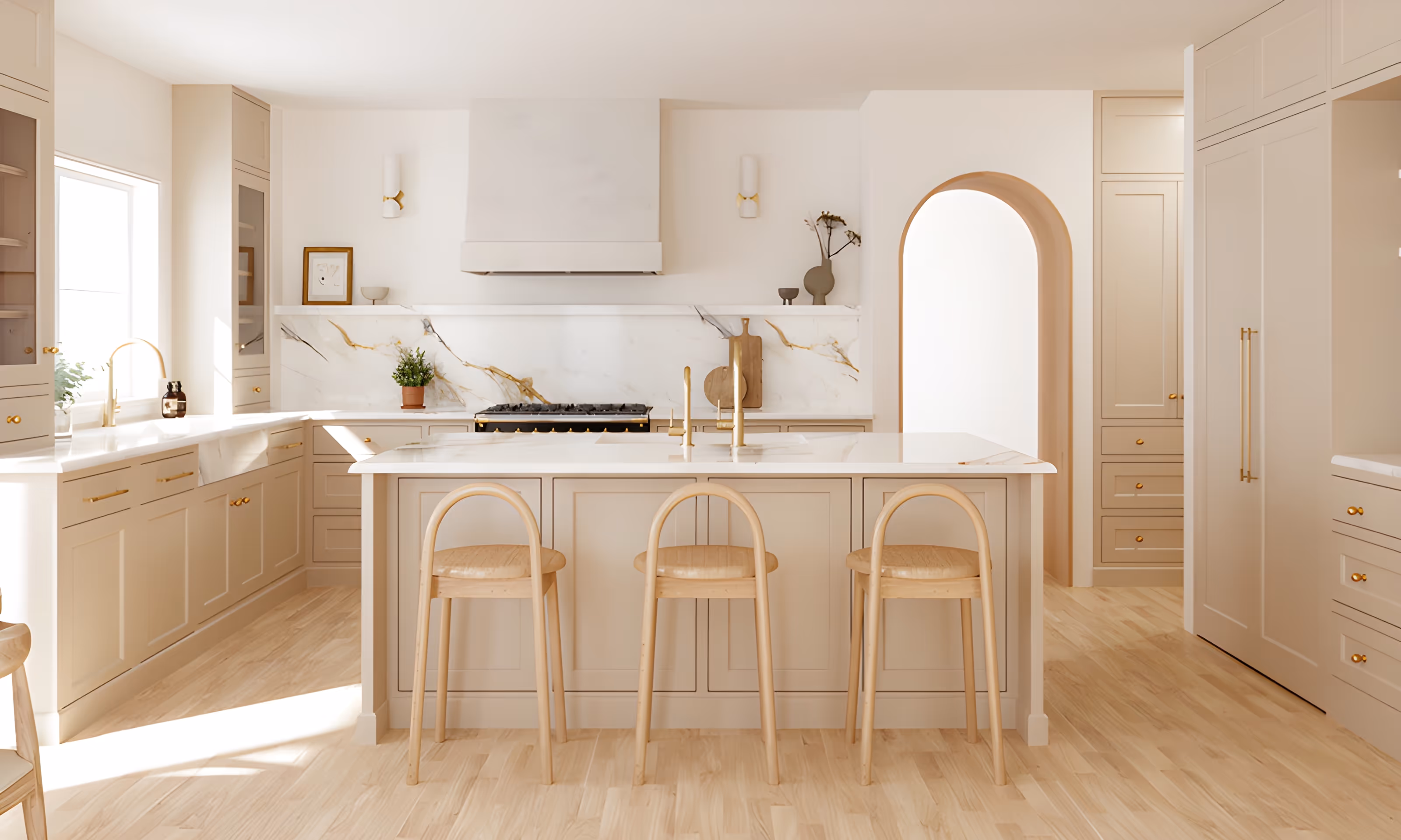 Bright modern kitchen with a large marble island, three wooden stools, beige cabinetry, gold fixtures, and an arched doorway.