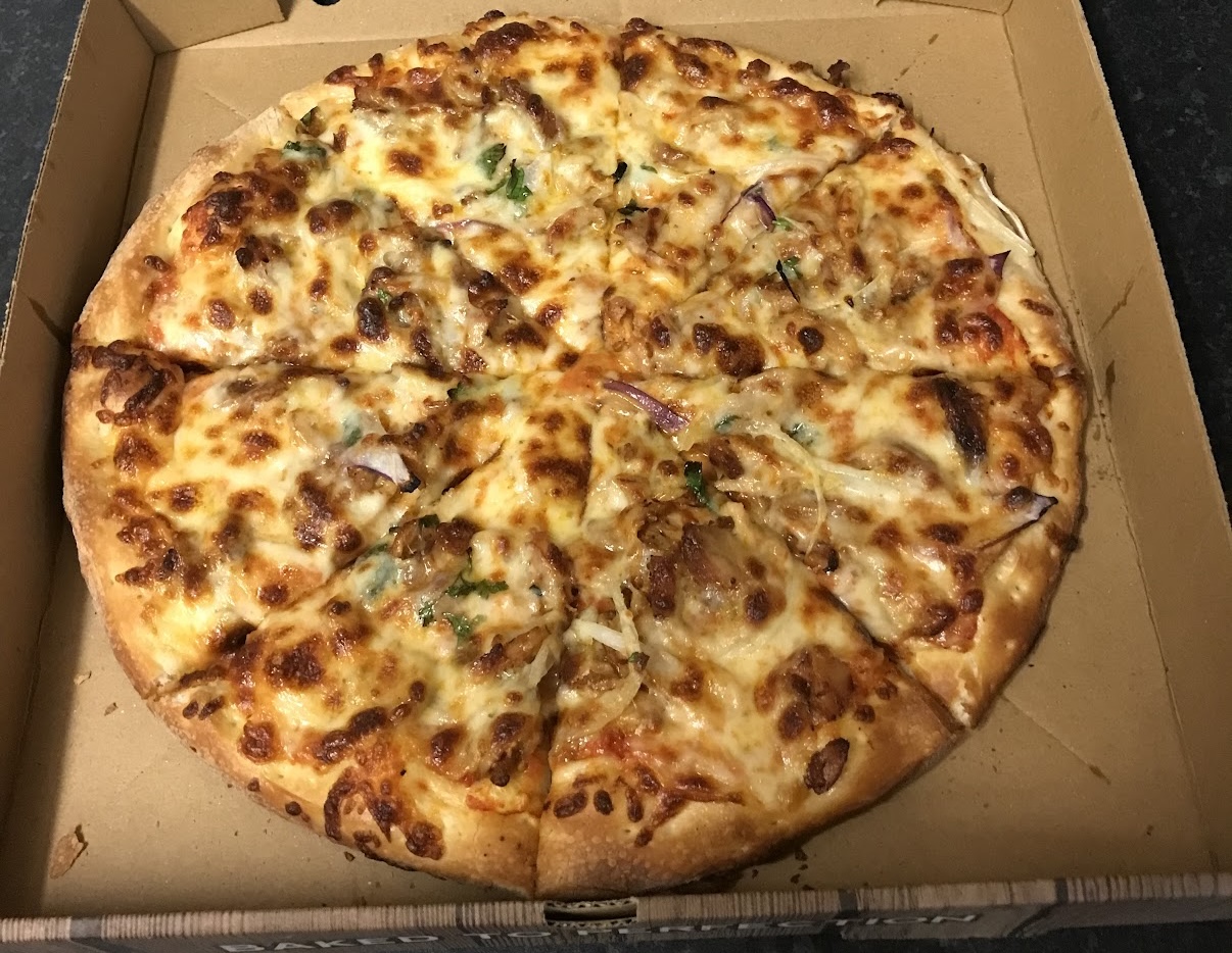 Whole cheese pizza with scattered green herbs in an open cardboard pizza box.