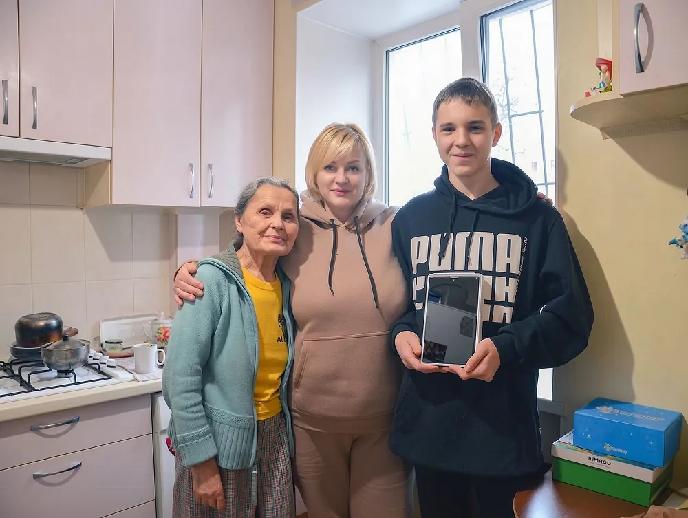 Бабуся, співробітниця фонду та хлопець із планшетом, отриманим завдяки підтримці фонду