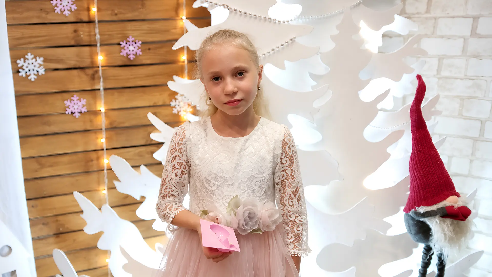 A girl in a festive dress by a Christmas photo backdrop during a Grow Up in a Family event